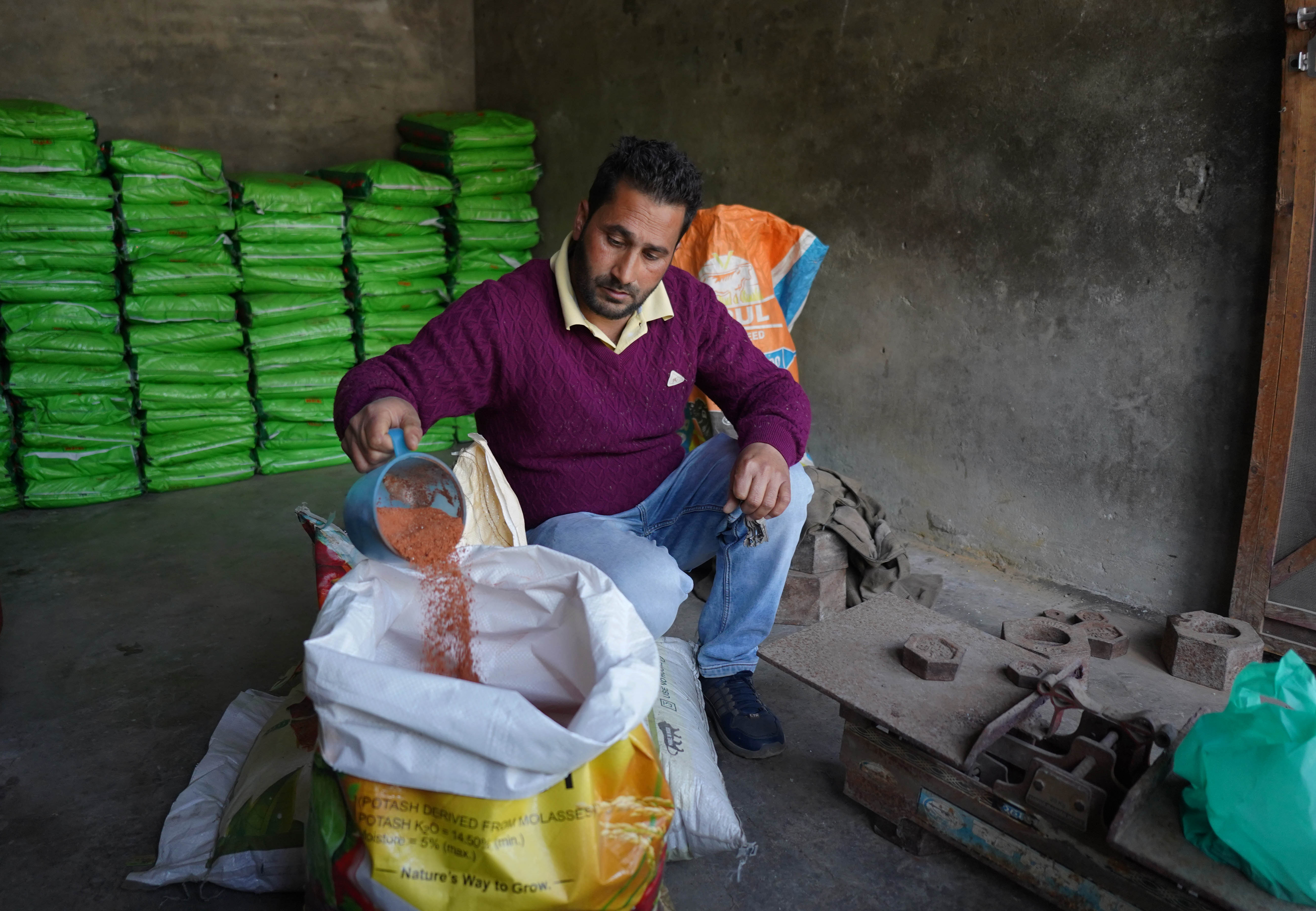 A worker pours fertiliser into a sack at a storage facility in Srinagar, Indian-administered Kashmir
