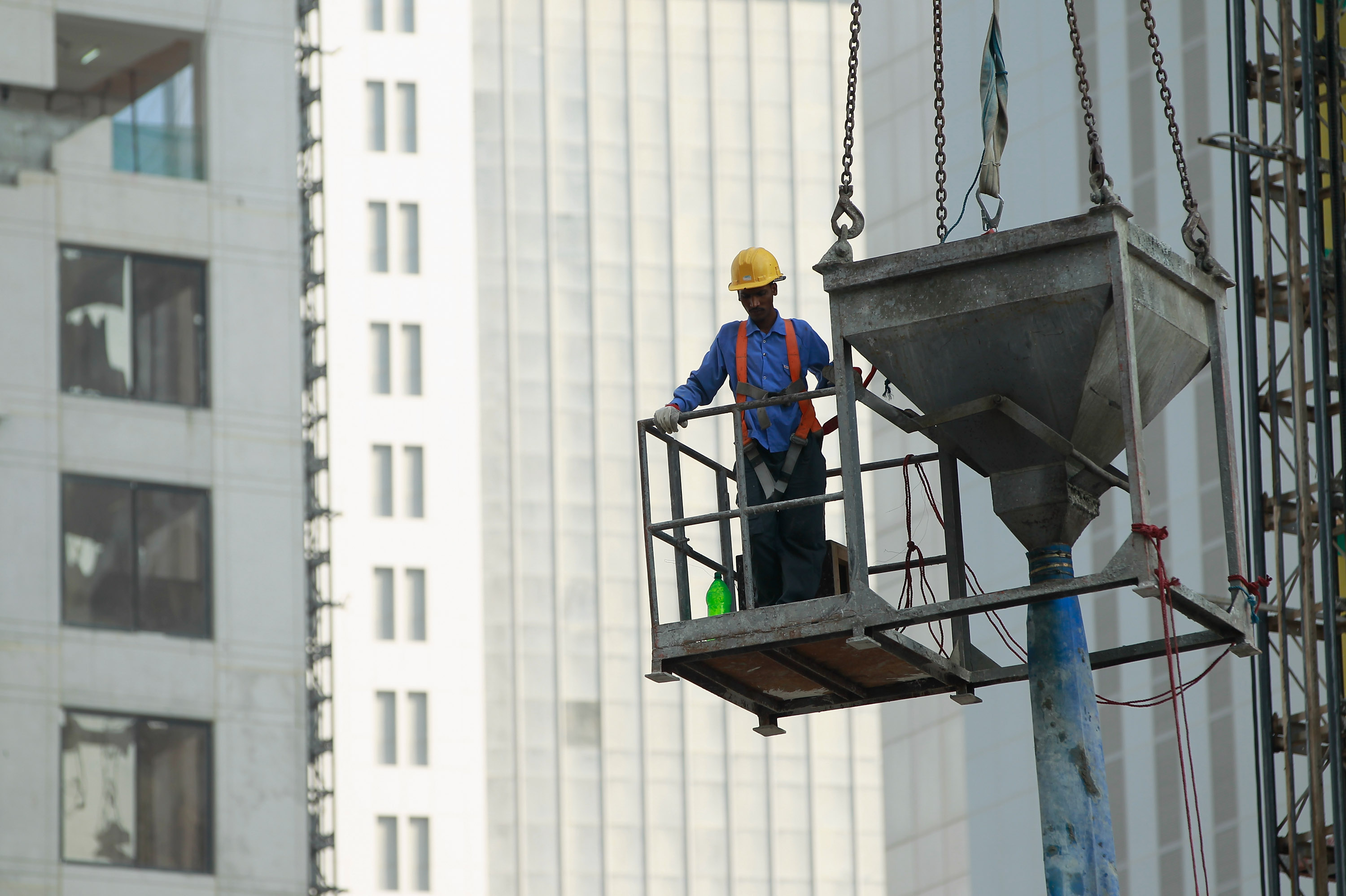 DOHA, QATAR - OCTOBER 24: A foreign worker helps guide a concrete funnel hoisted by a crane at a construction site among new highrise office buildings and hotels under construction in the new City Center and West Bay district on October 24, 2010 in Doha, Qatar. The International Monetary Fund (IMF) recently reiterated its projection for the Qatari economy with predictions of double digit growth for 2010 and 2011. Though natural gas and petroleum production are still the biggest two single sources of income, the non-energy sector overtook oil and gas in Qatari GDP for 2009. Qatar is heavily dependant on foreign labour from countries such as India, Sri Lanka, Bangladesh, the Phillipines and other Arab countries. Foreigners make up approximately two thirds of the Qatari population. (Photo by Sean Gallup/Getty Images)