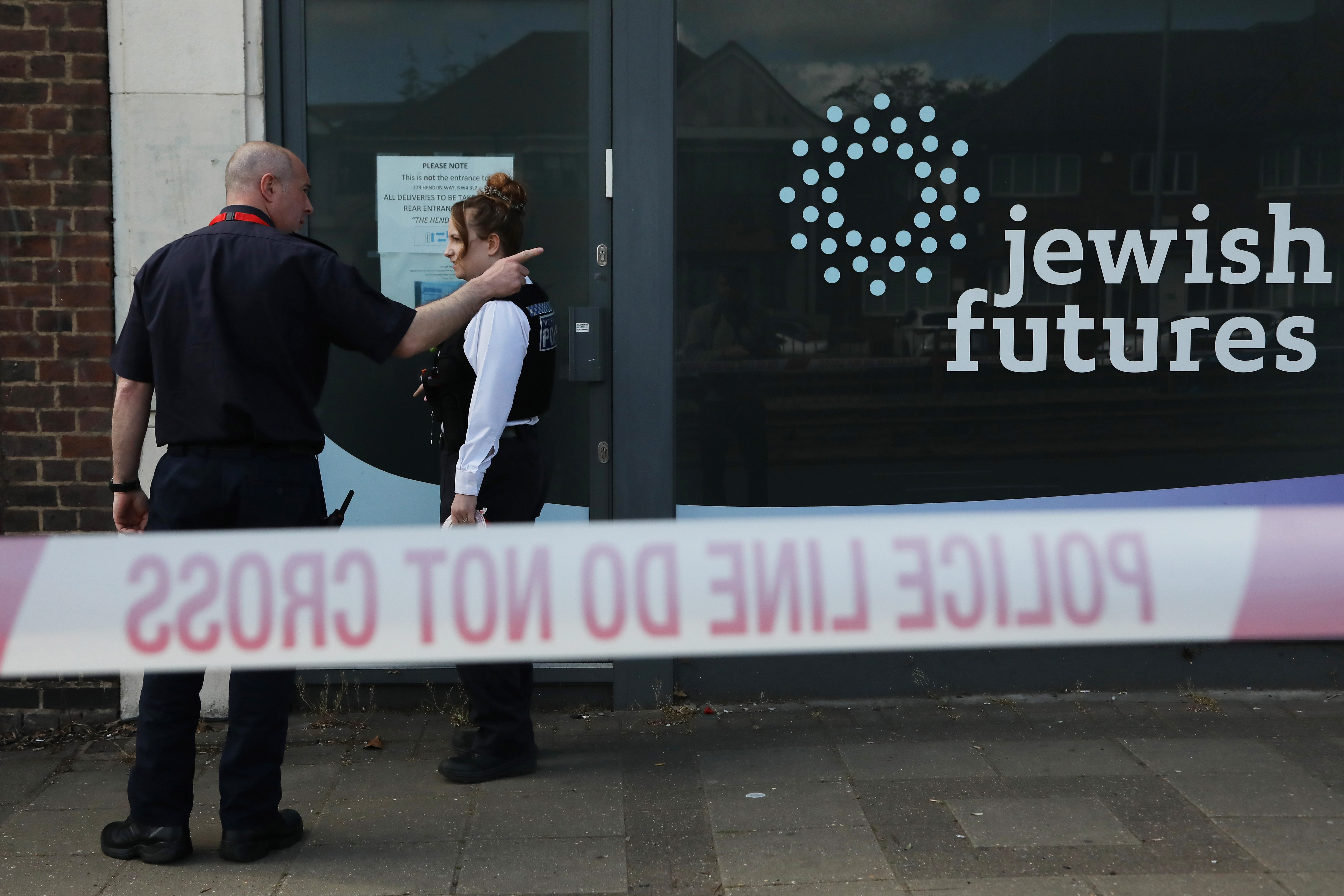HENDON, ENGLAND - APRIL 18: Police officers stand beyond a cordon as police investigate the scene of an attempted arson attack on April 18, 2026 in the Hendon area of London, England. The Metropolitan Police said its officers were called to the location around 10:30pm last night after a man approached a row of shops carrying a bag with three bottles of fluid and tried to set them alight, before fleeing the scene. (Photo by Alishia Abodunde/Getty Images)