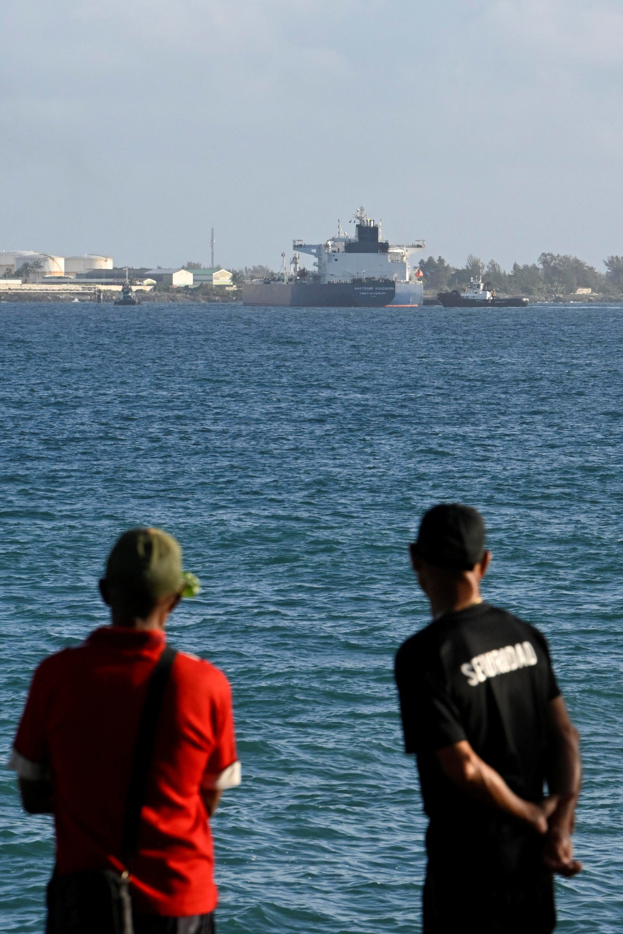 People watch as Anatoly Kolodkin, a Russian-flagged oil tanker carrying some 700,000 barrels of crude, marking the first significant oil delivery since the administration of U.S. President Donald Trump cut off Cuba's fuel supply, is moored while being assisted by tugboats, at Matanzas oil terminal, in Matanzas, Cuba, March 31, 2026. REUTERS/Norlys Perez