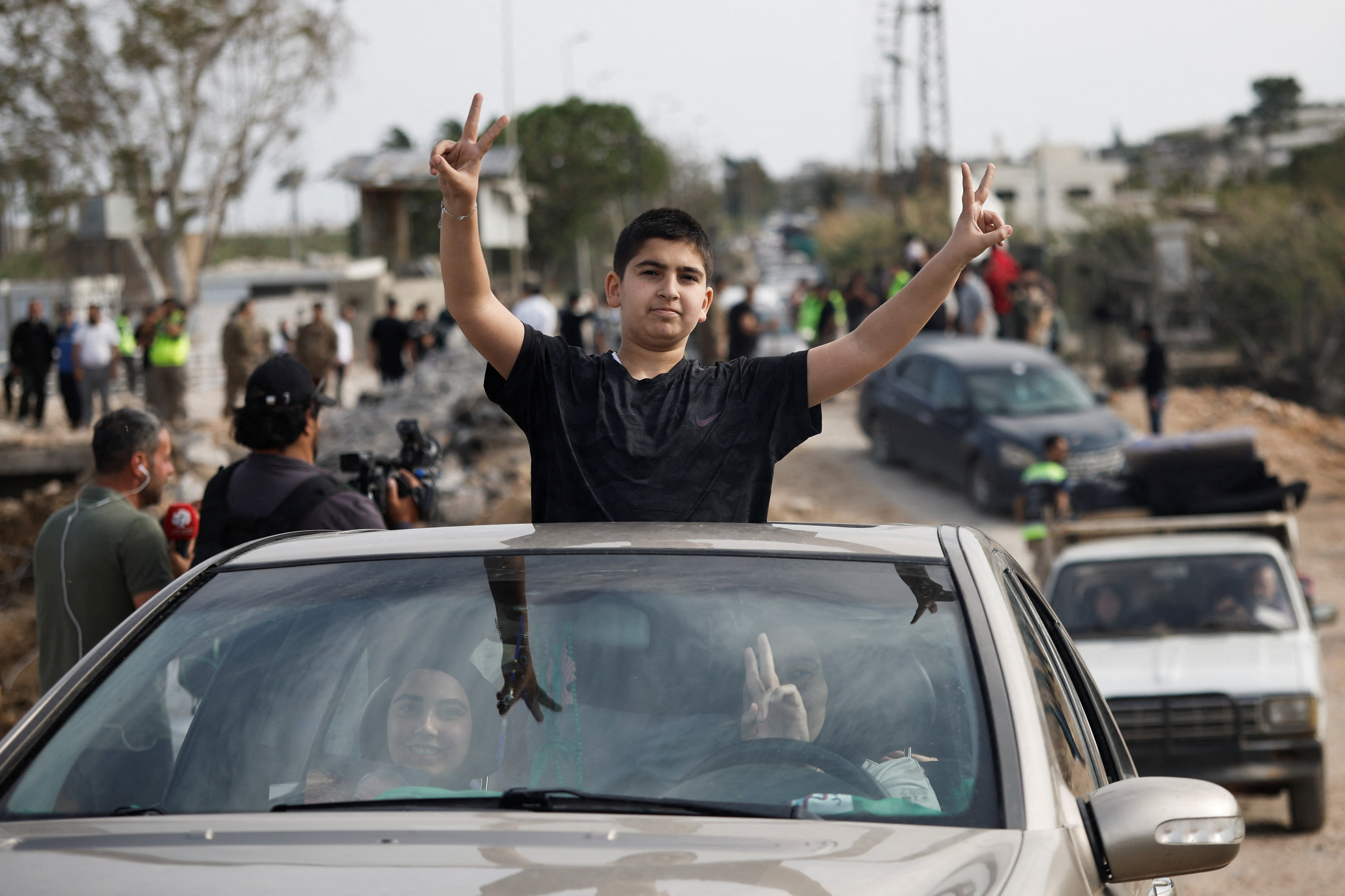 People show victory signs from a vehicle as displaced people make their way back to their homes crossing the bridge linking southern Lebanon to the rest of the country, which was hit earlier in an Israeli strike, after a 10-day ceasefire between Lebanon and Israel went into effect, in Qasmiyeh, Lebanon, April 17, 2026. REUTERS/Louisa Gouliamaki