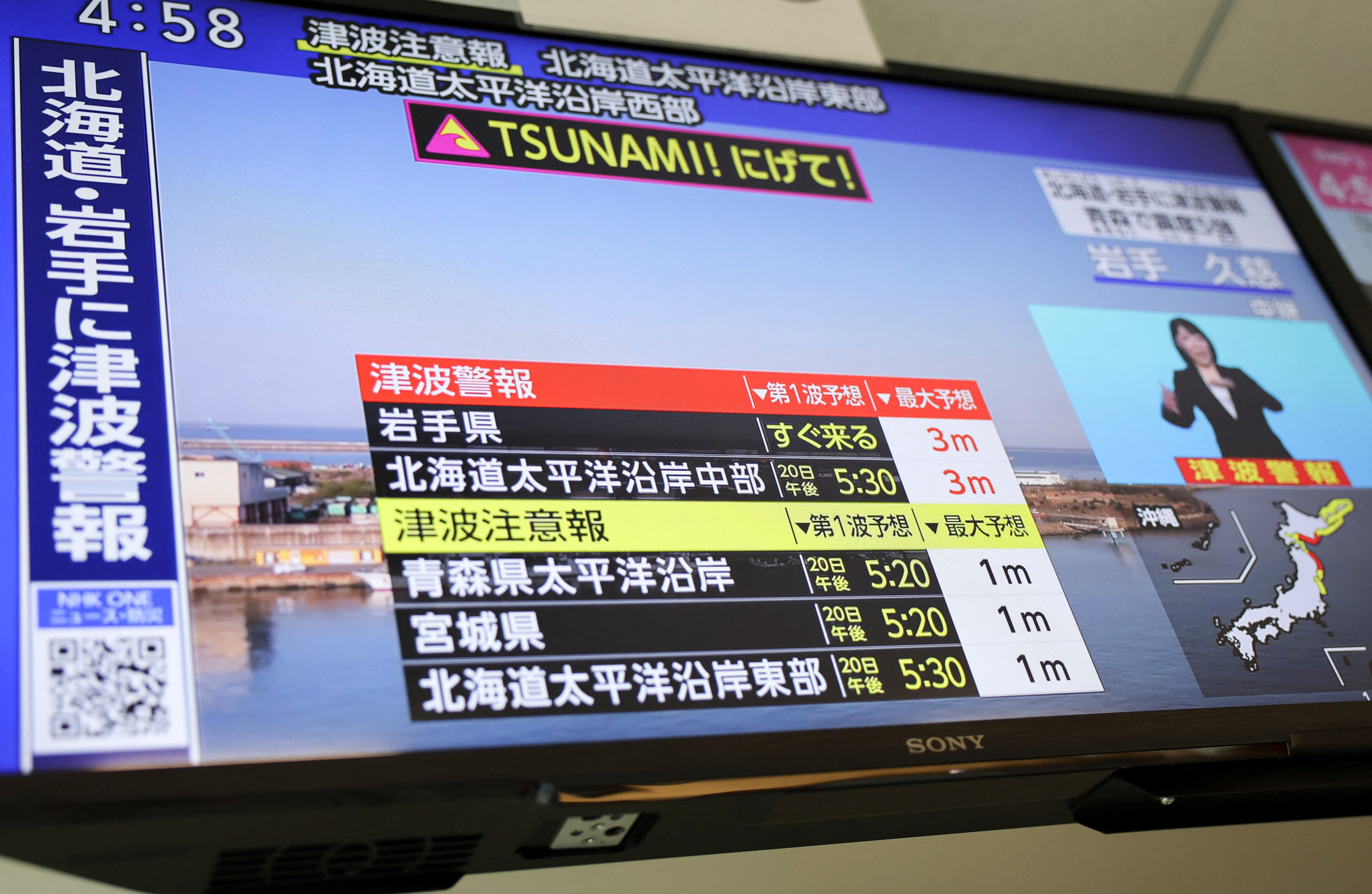 A TV screen shows a news report on Japan Meteorological Agency's tsunami warning in Tokyo