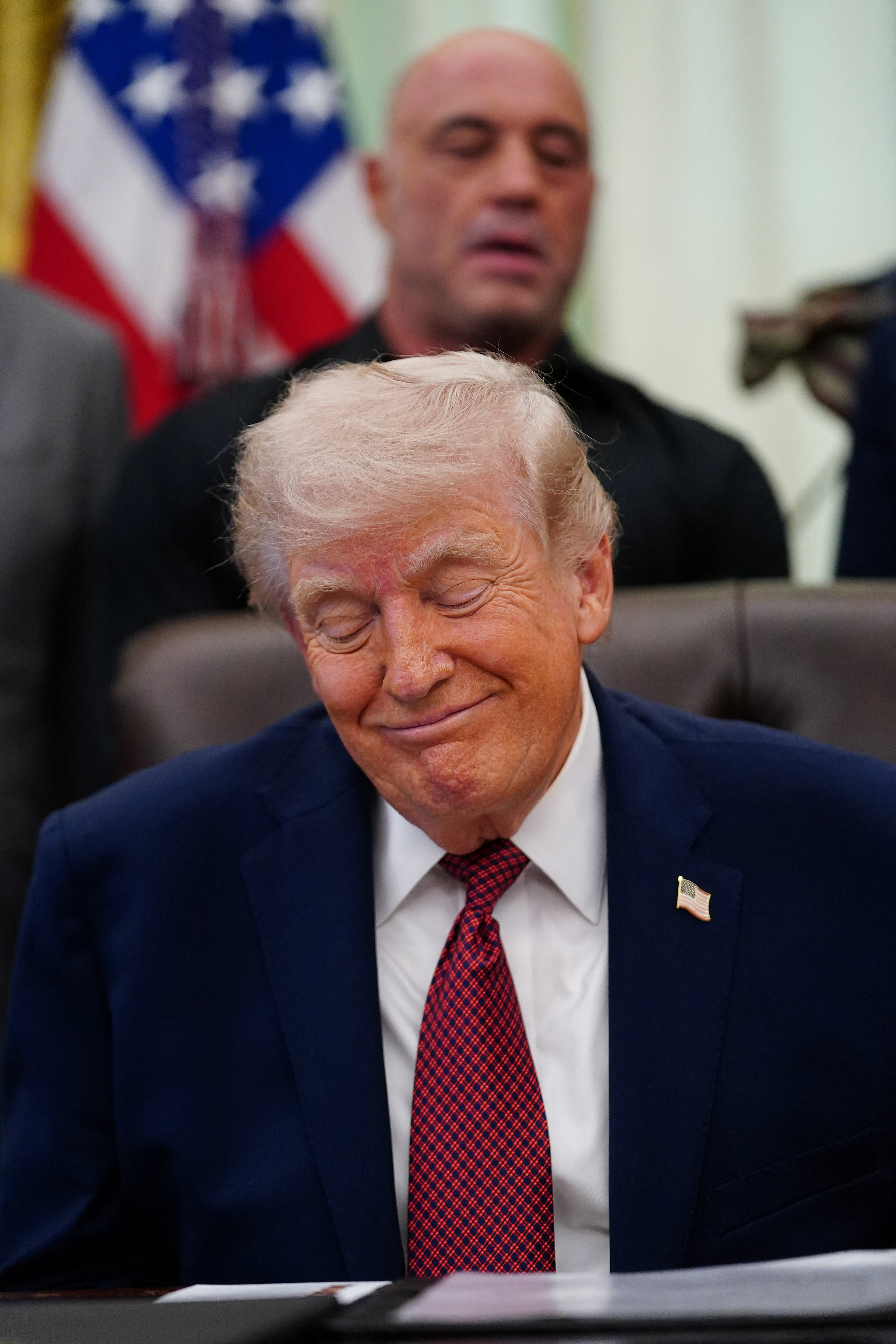 U.S. President Donald Trump sits in front of podcaster Joe Rogan, on the day President Trump signs an executive order about easing restrictions on mental health treatments, including, ibogaine, in the Oval Office of the White House in Washington, D.C., U.S. April 18, 2026. REUTERS/Nathan Howard