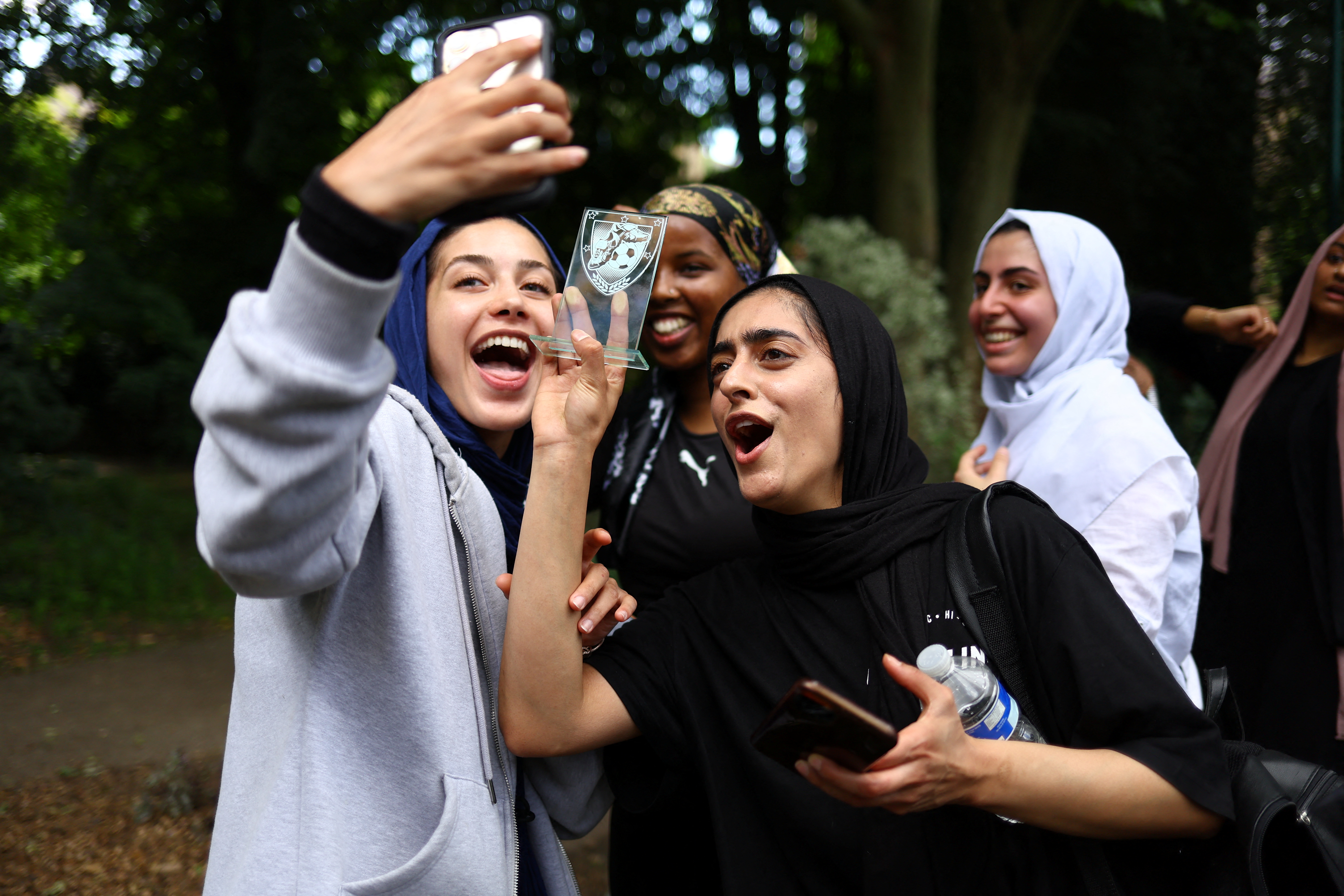 Fatima Ali, 26, and Sara Taleghani, 25, video-call Yasmin Abdullahi, 30, the founder of Sisterhood FC, to celebrate their first match win, at The Colombo Centre in London, Britain, June 12, 2022. Founded in 2018, Sisterhood FC has doubled in size to almost 100 players, allowing Muslim women a chance to enjoy a break from traditional roles that many say are expected of them. "If there had been spaces like this when we were growing up, I know a few girls who would have made it as pros," Taleghani said. REUTERS/Hannah McKay SEARCH "MCKAY SISTERHOOD FC" FOR THIS STORY. SEARCH "WIDER IMAGE" FOR ALL STORIES.