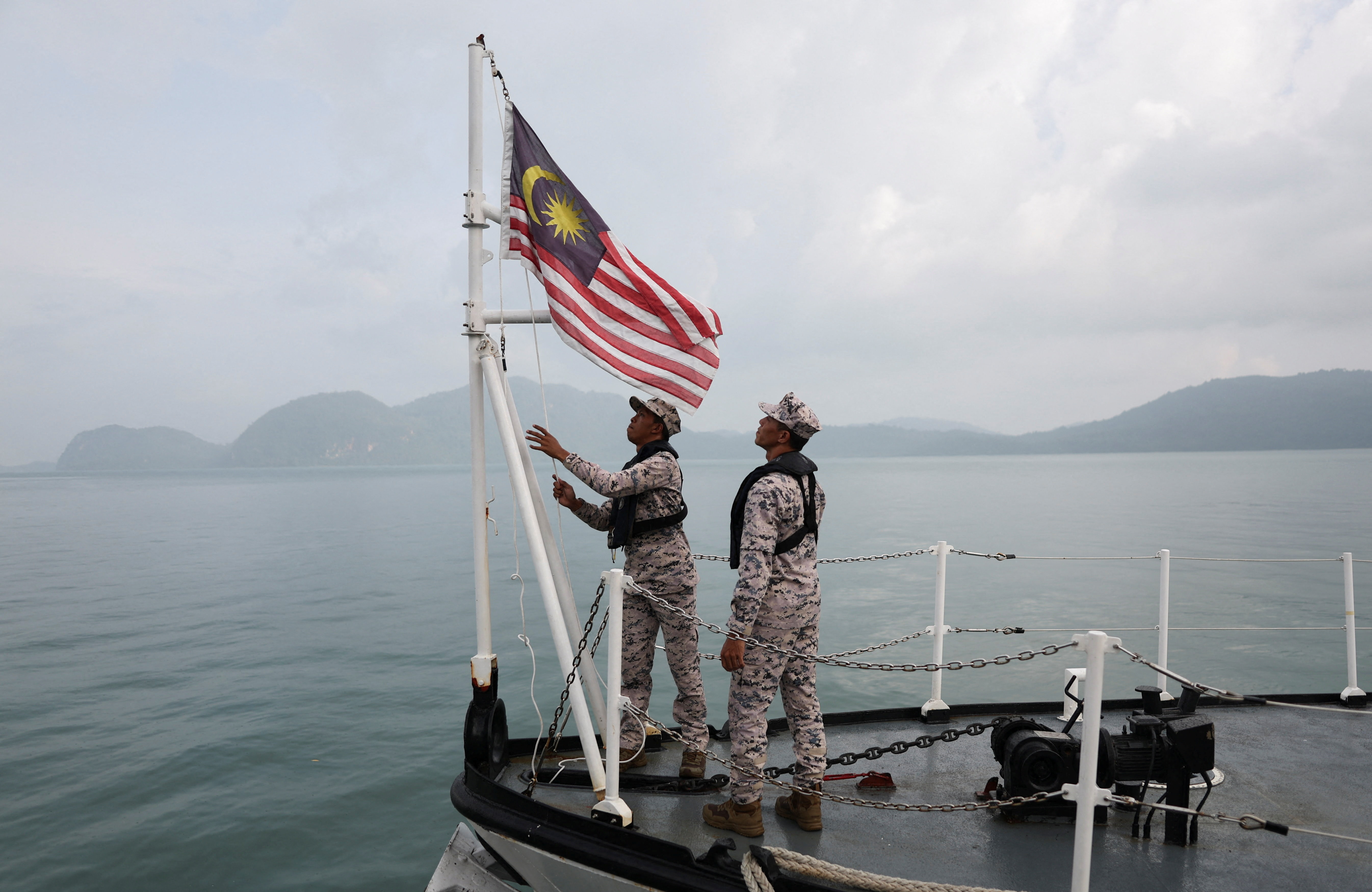MMEA officers lower the Malaysian flag as they prepare to depart for a search and rescue operation