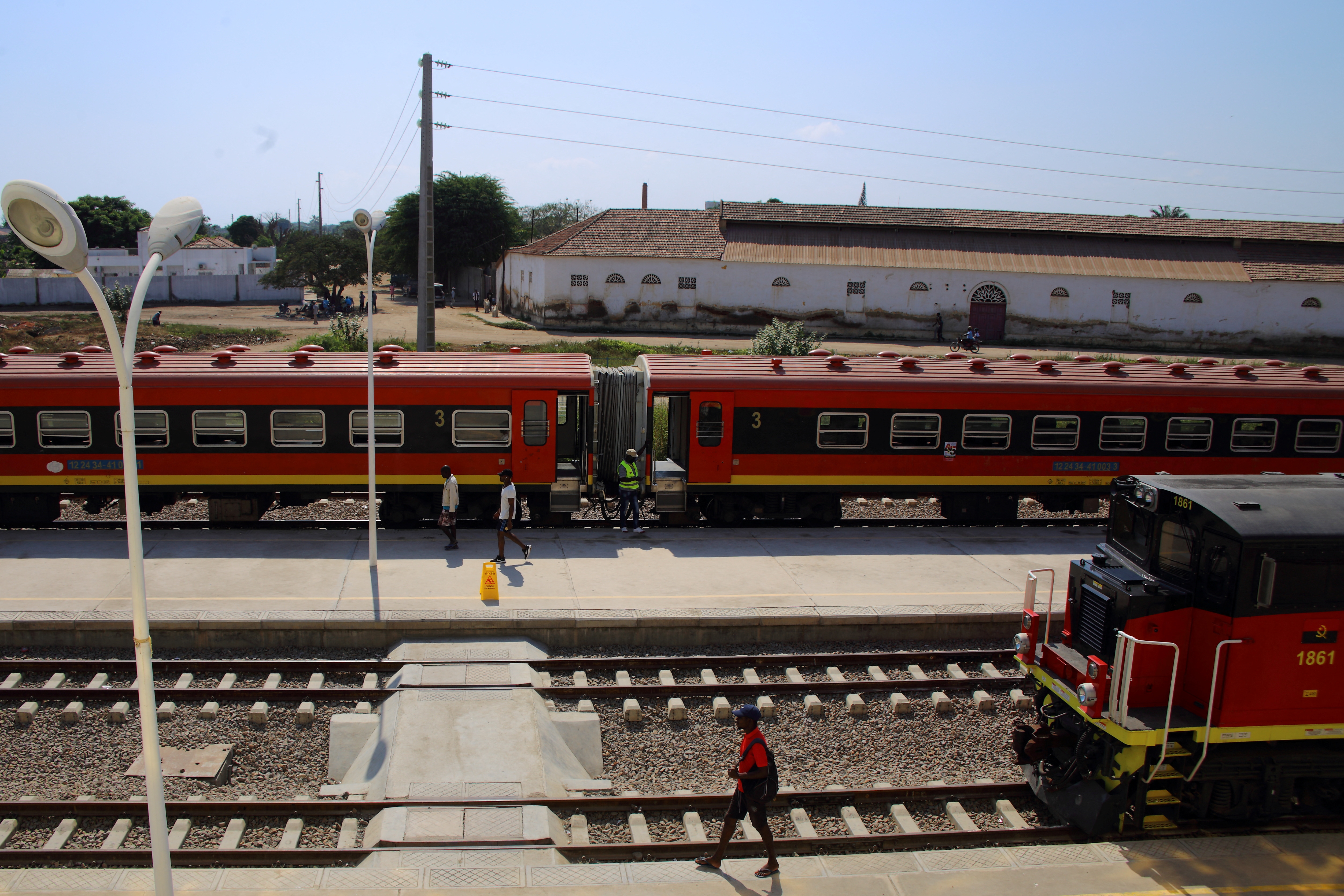 People walk past trains parked at a station.