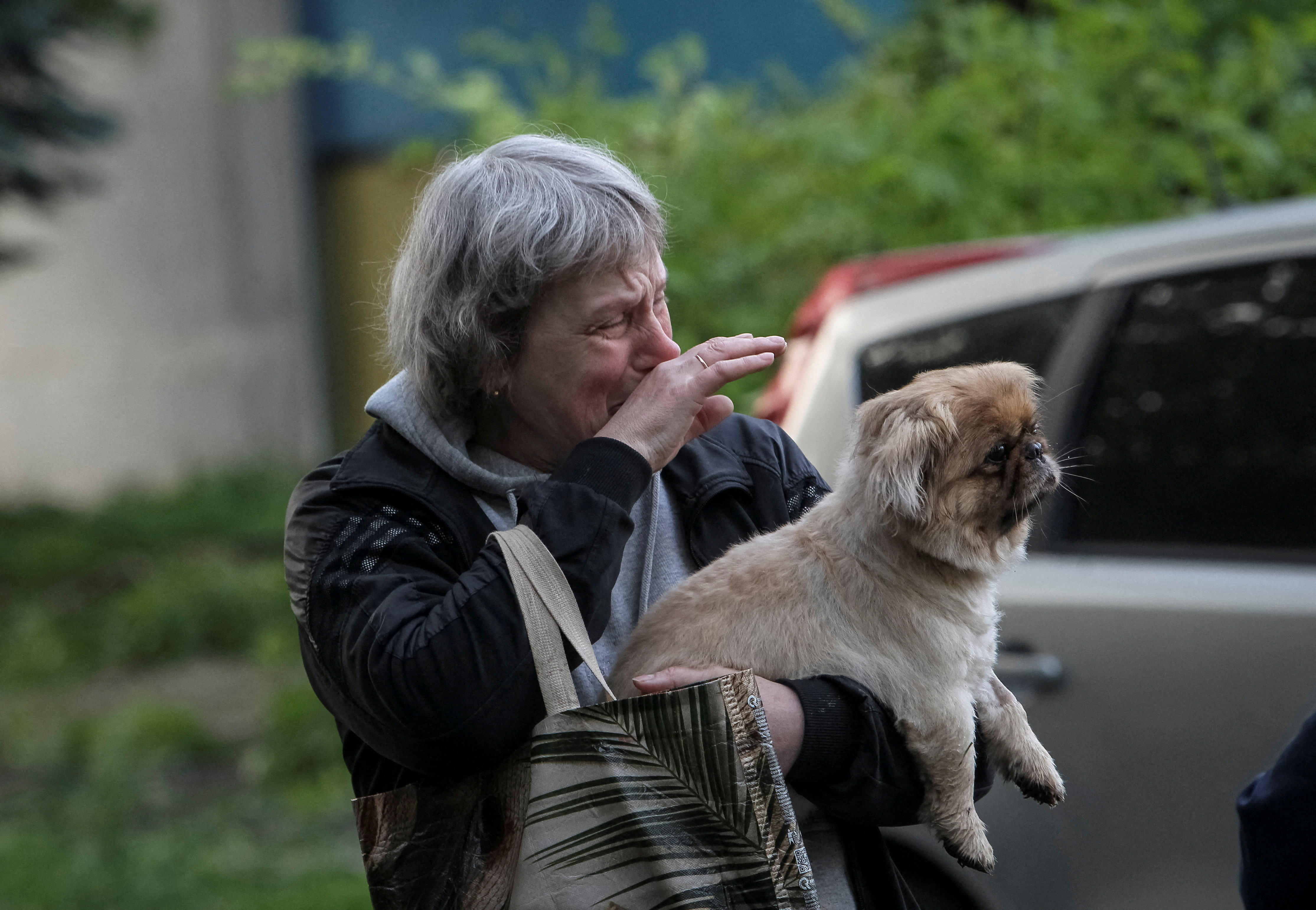 A woman reacts as she stands holding a dog.