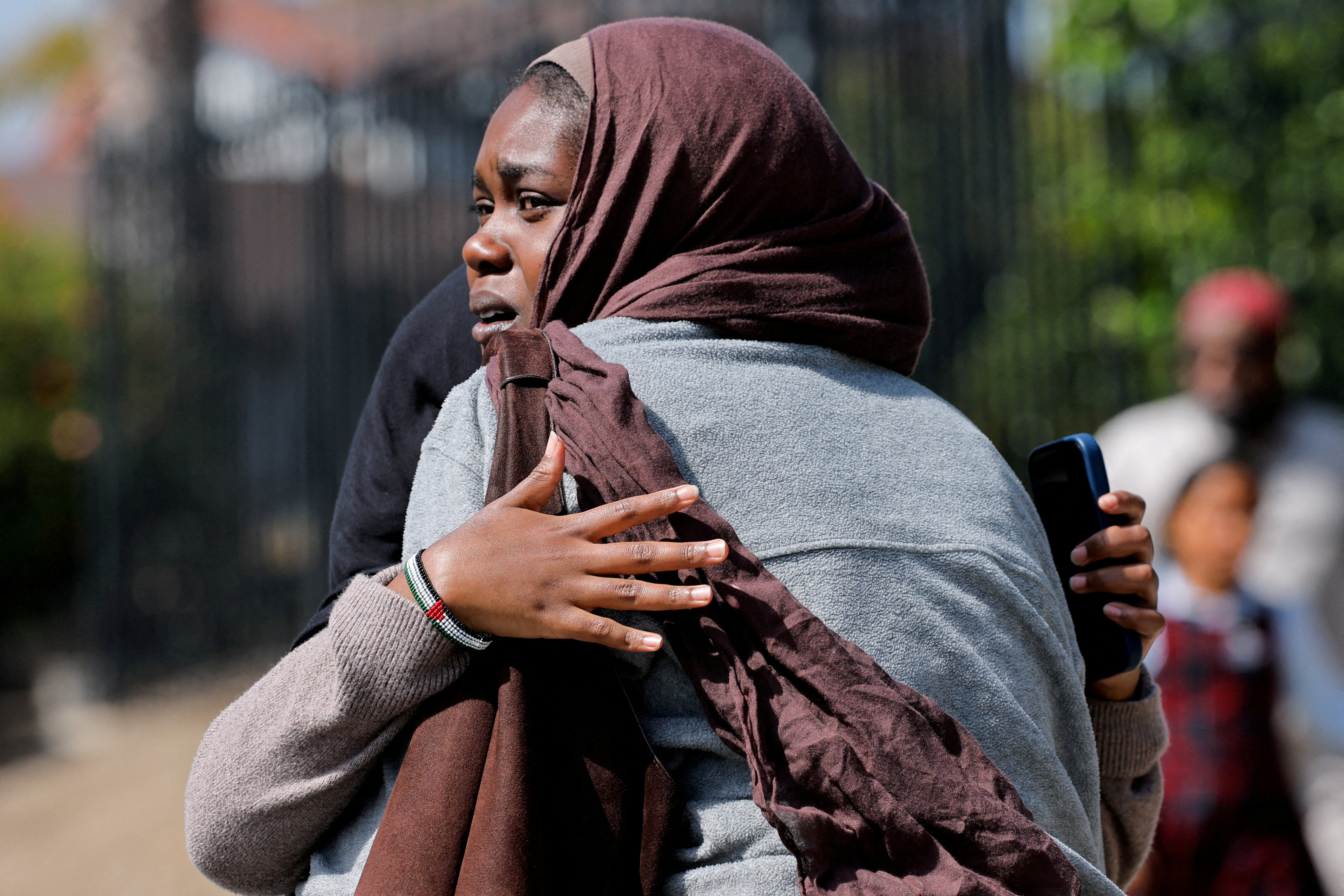 Women hug as they wait for the children to walk out of the mosque, at a collecting area, at the scene of a shooting at the Islamic Center in San Diego, California, U.S., May 18, 2026. [Mike Blake/Reuters]