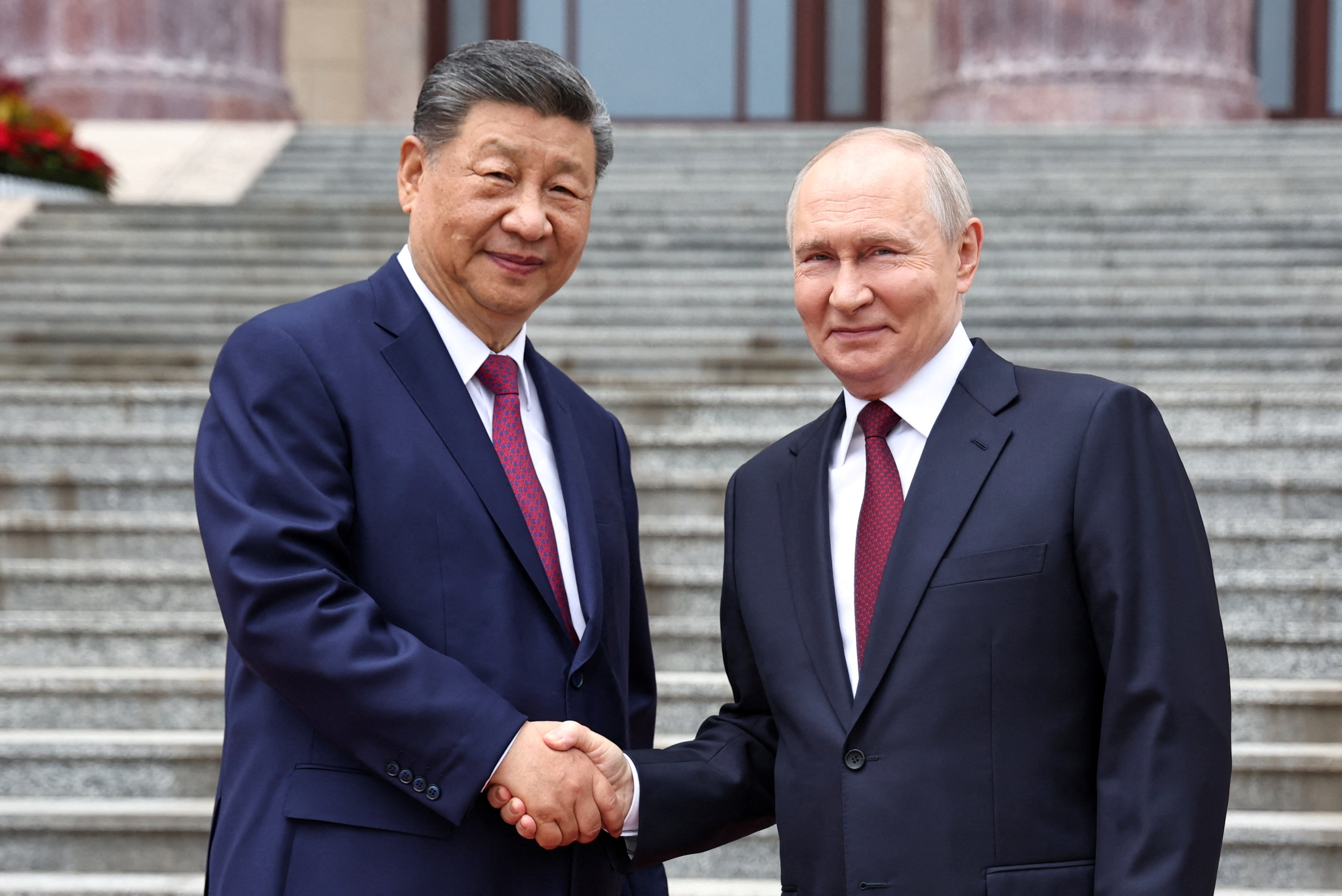 Russian President Vladimir Putin shakes hands with Chinese President Xi Jinping