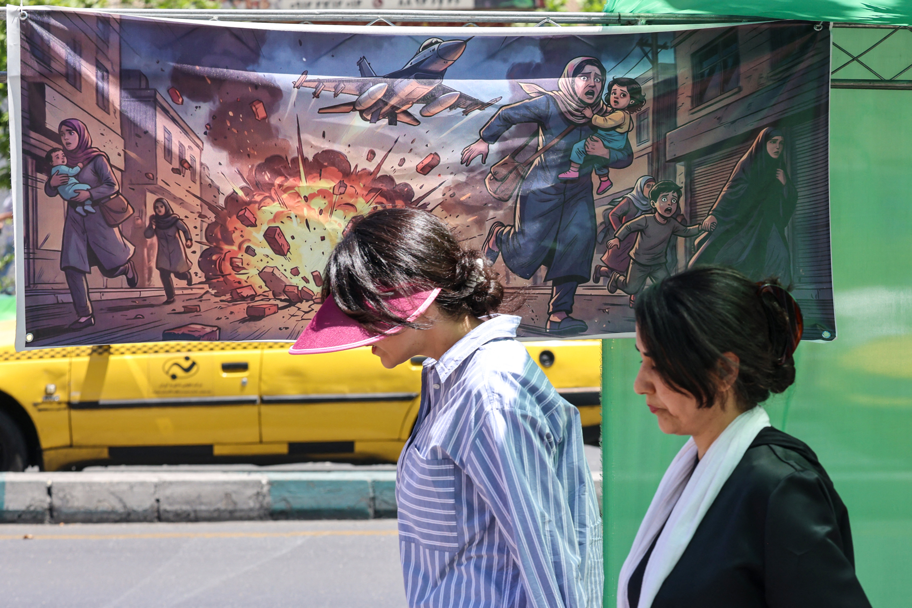 An Iranian woman walks past a banner depicting the US-Israel military attacks on Iran, in the capital Tehran on May 9, 2026. Iran questioned the seriousness of American diplomacy on May 9, in the wake of renewed naval clashes in the Gulf, while keeping Washington waiting for a response to its latest negotiating position. On February 28, 2026, Israel and the United States launched strikes on Iran, killing its supreme leader and triggering a war that spread across the Middle East. (Photo by ATTA KENARE / AFP) /