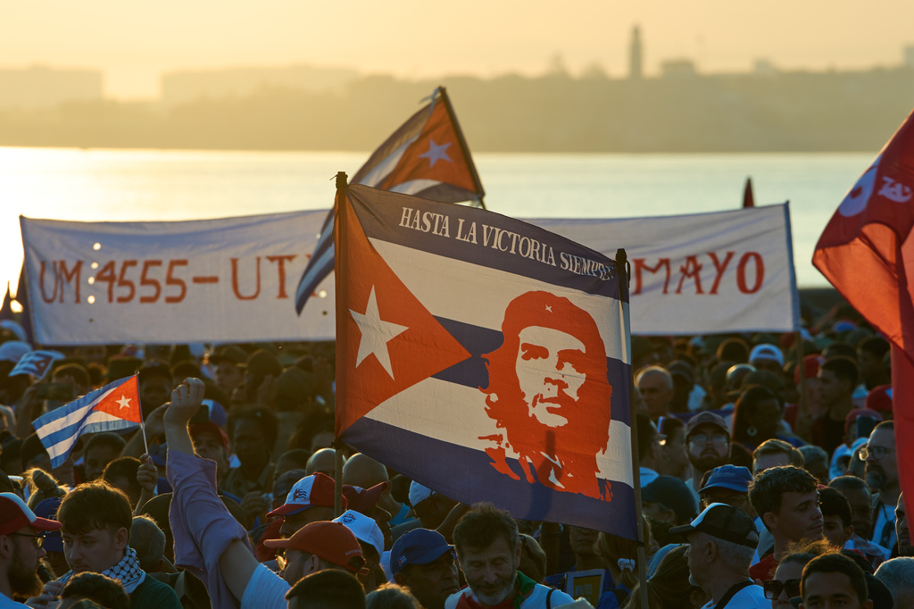 People hold banners of Che Guevara at a march in Havana