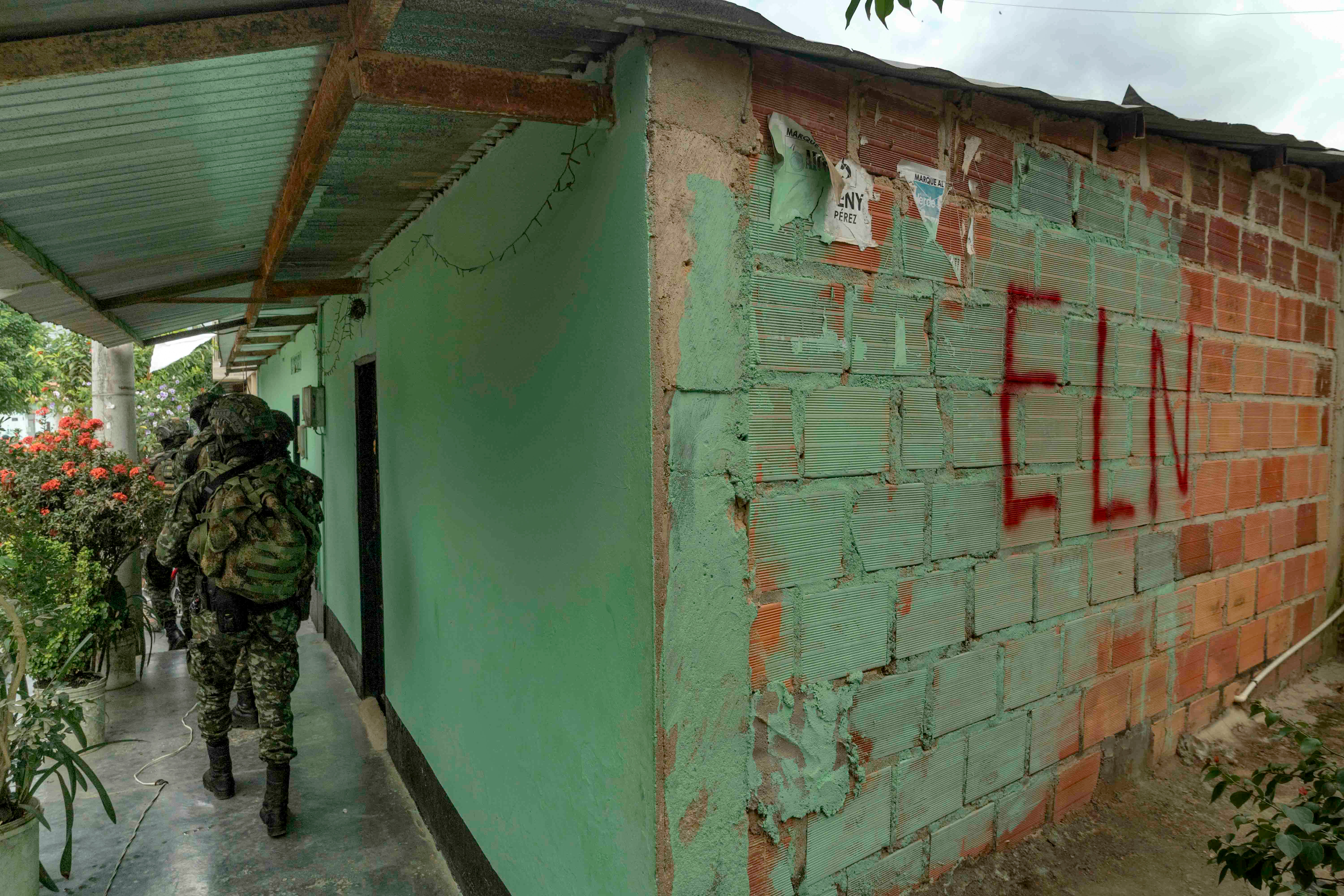 Colombian soldiers on patrol near a building with'ELN' in spraypaint