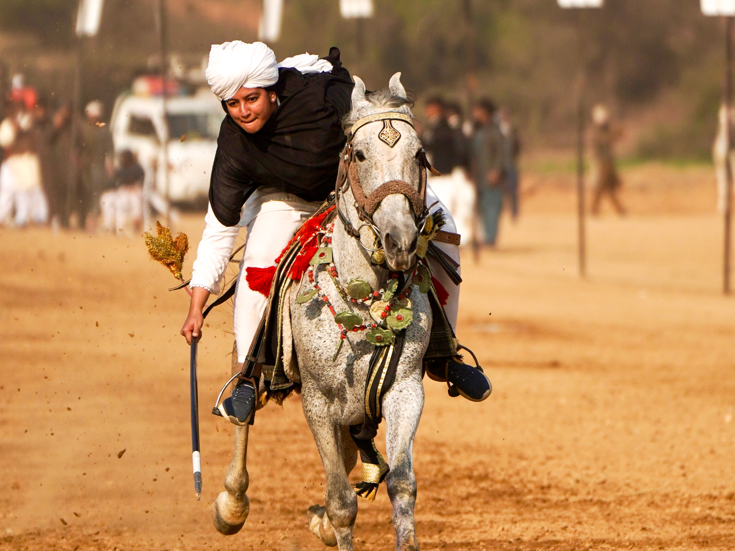 Anum Shakoor dips with her lance to pierce a wooden peg during a tent pegging competition [Mutee Ur Rehman/Al Jazeera]
