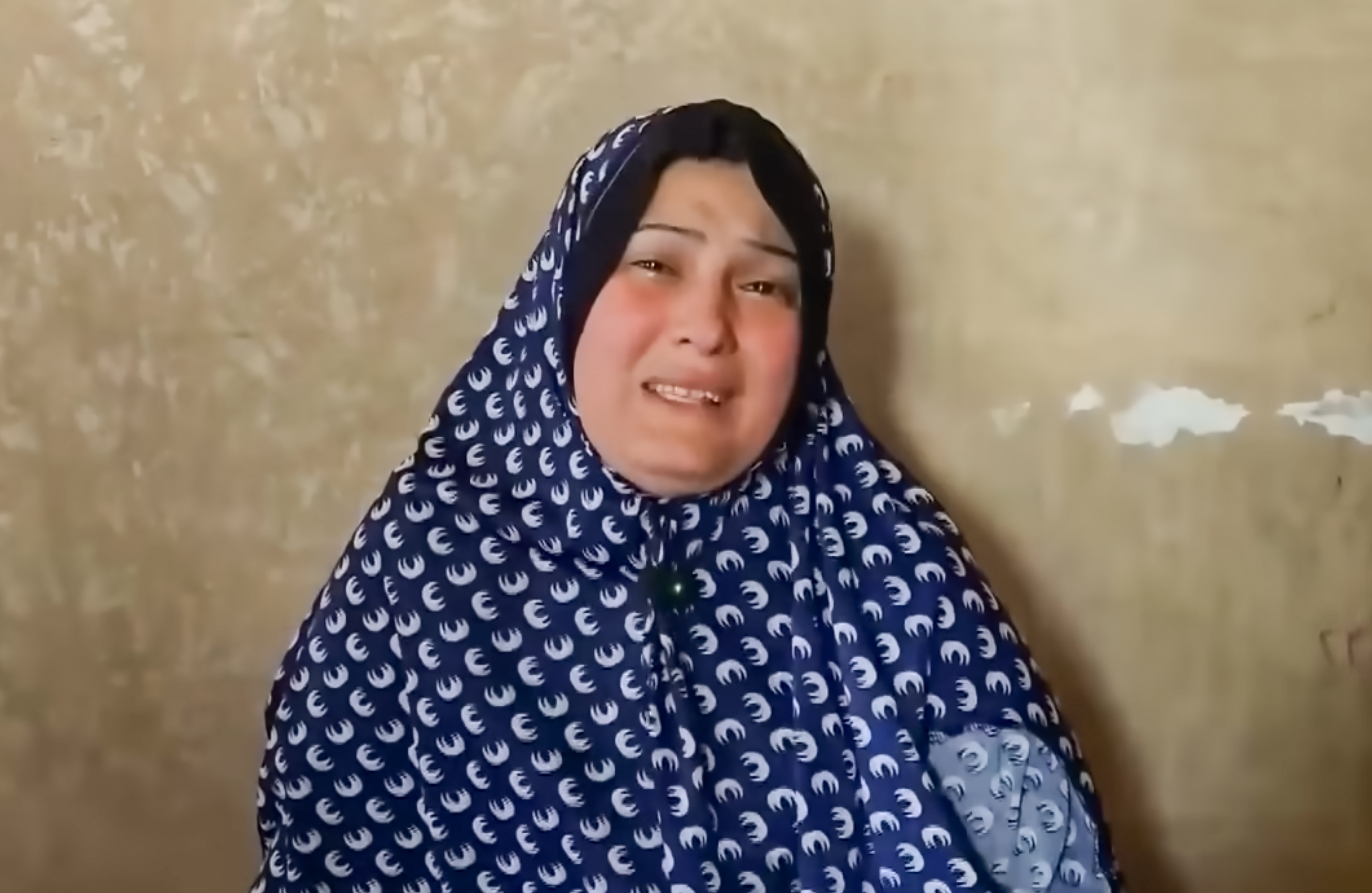 Gaza mother Maha Abu Al-Shaar holds her phone displaying a photo of her son, Eid, as she cries with joy and sadness after discovery that he is alive in an Israeli prison, 18 months after being declared a martyr and missing. [Screengrab/Al Jazeera]