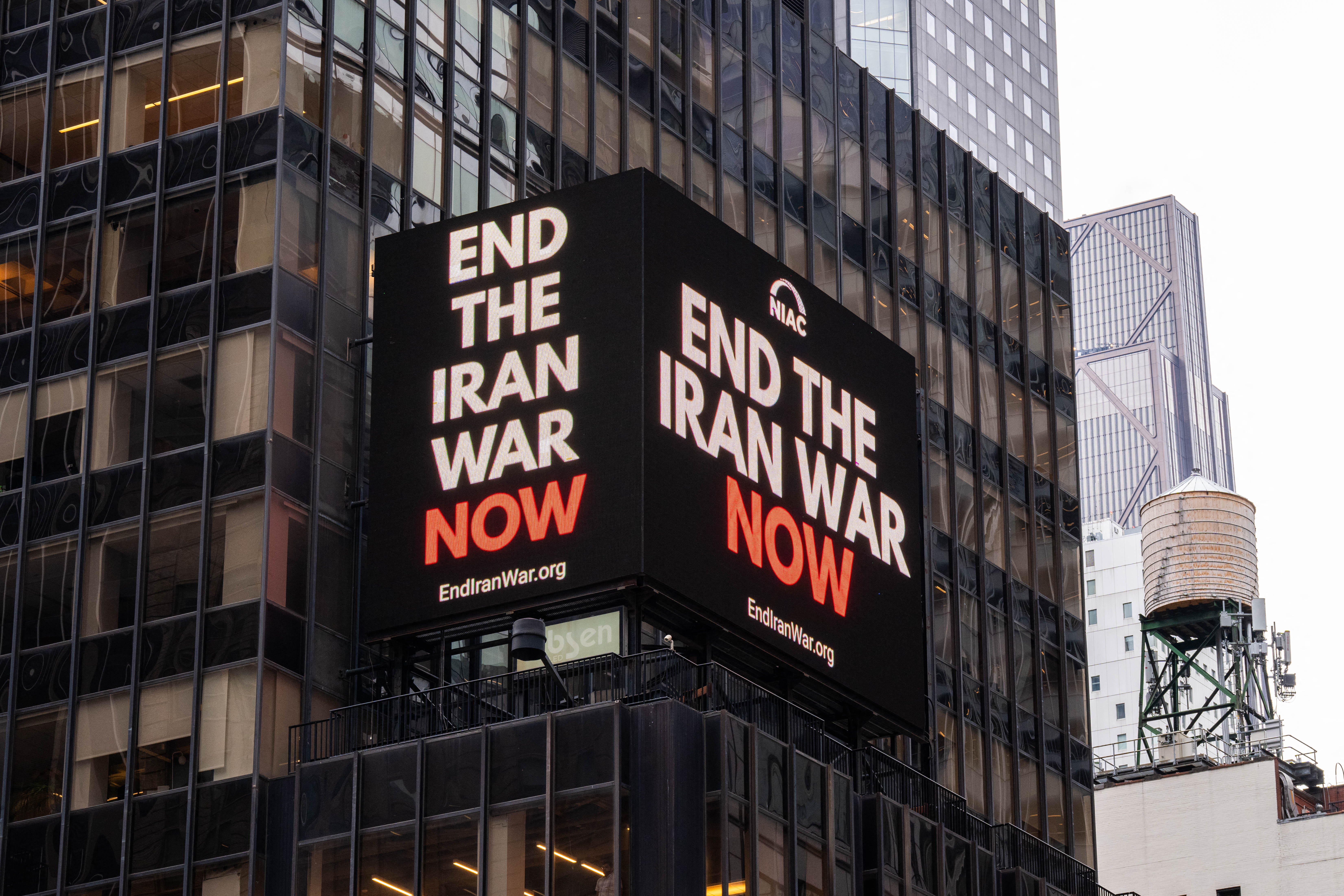 A digital billboard displays an image reading 'end the Iran war now' New York