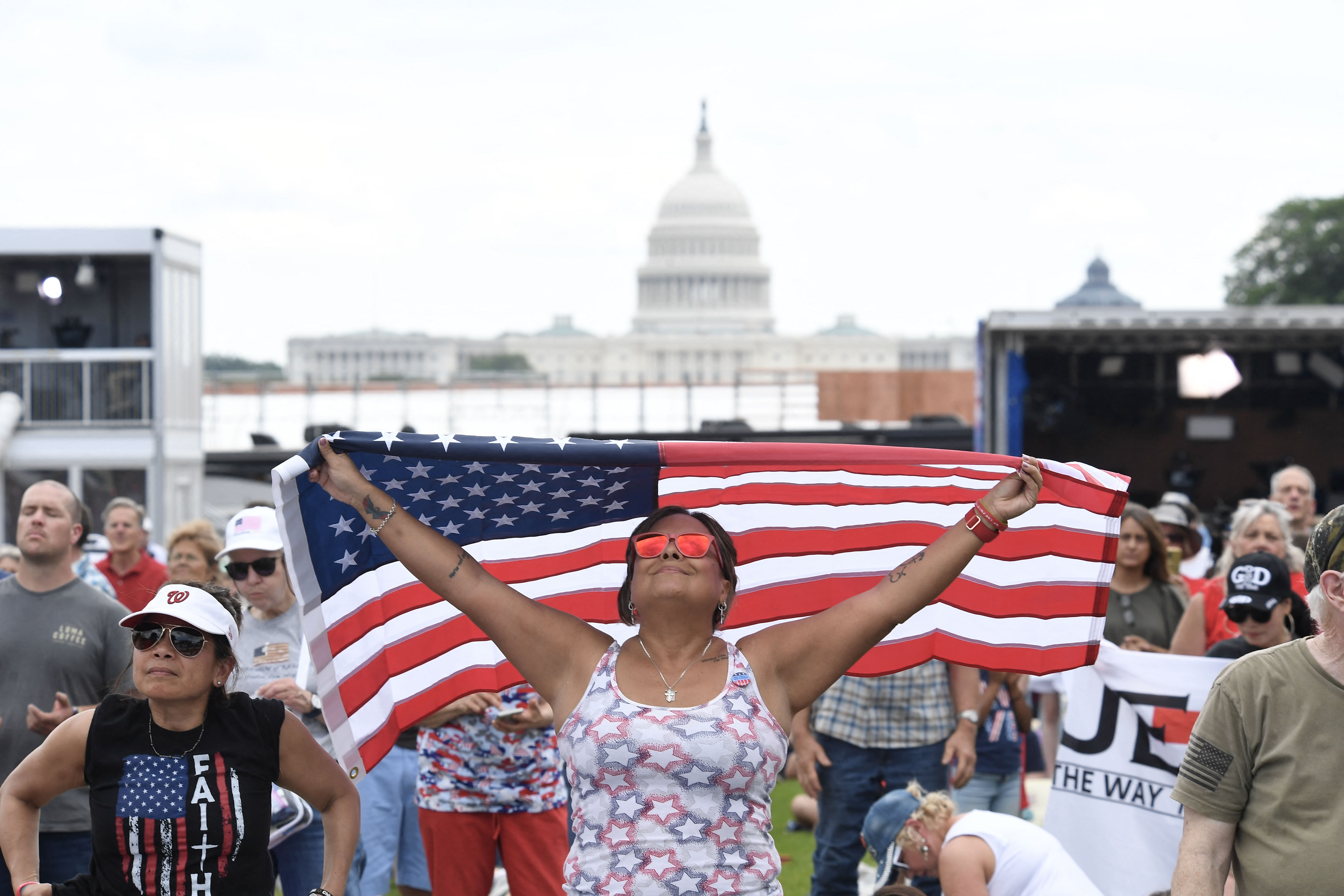 An attendee holds an American flag over her head during "Rededicate 250: A National Jubilee of Prayer, Praise and Thanksgiving" on the National Mall in Washington, DC, on May 17, 2026.