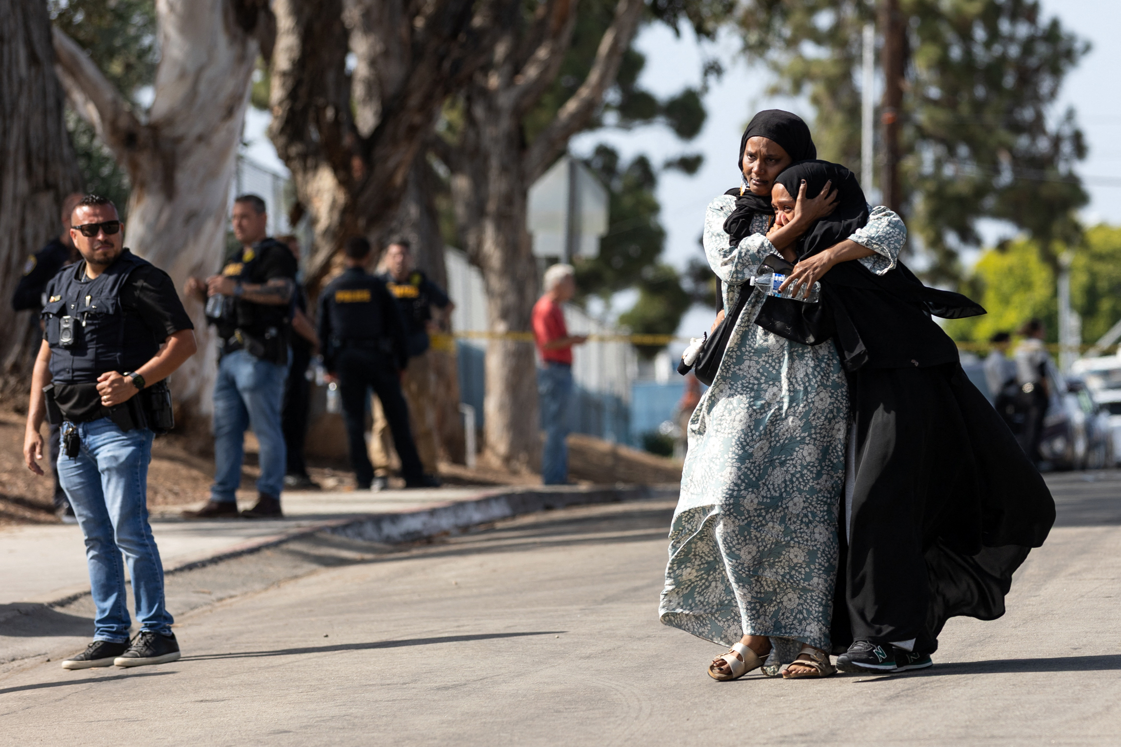 TOPSHOT - Two women react as they leave a reunification center following the shooting at the Islamic Center of San Diego in southern California, on May 18, 2026.