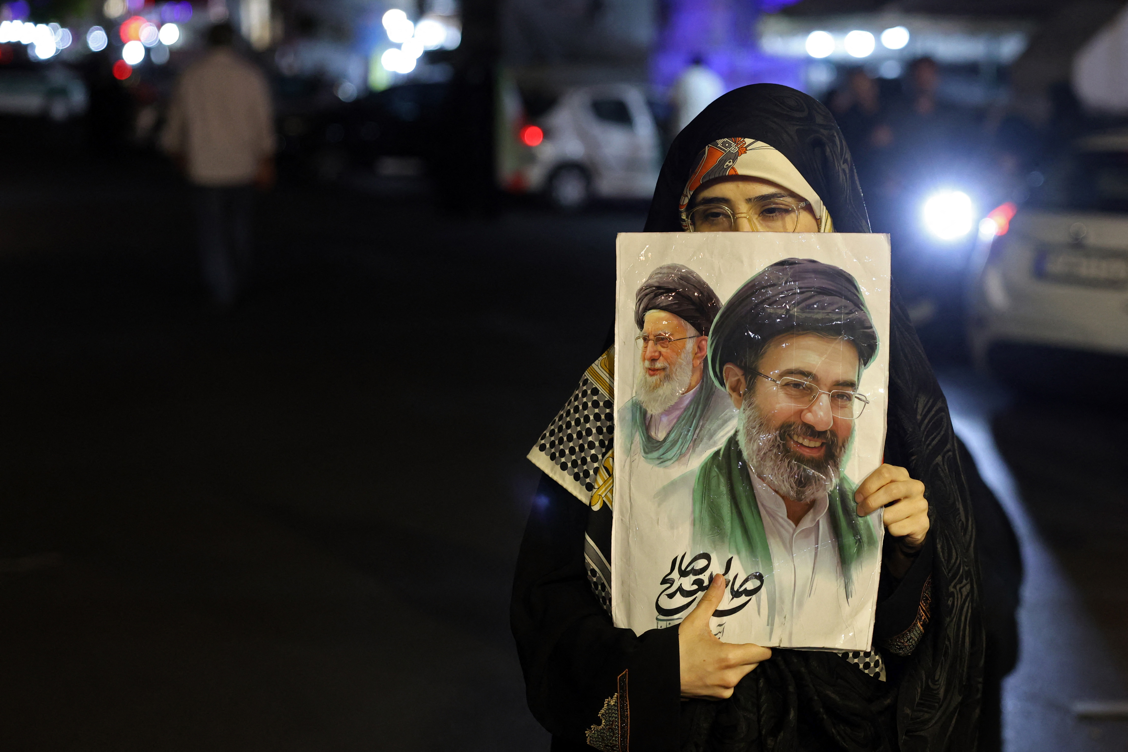 A woman holds a placard with photos of Iran's Supreme Leader Ayatollah Mojtaba Khamenei and his predecessor and late father Ayatollah Ali Khamenei during a protest.