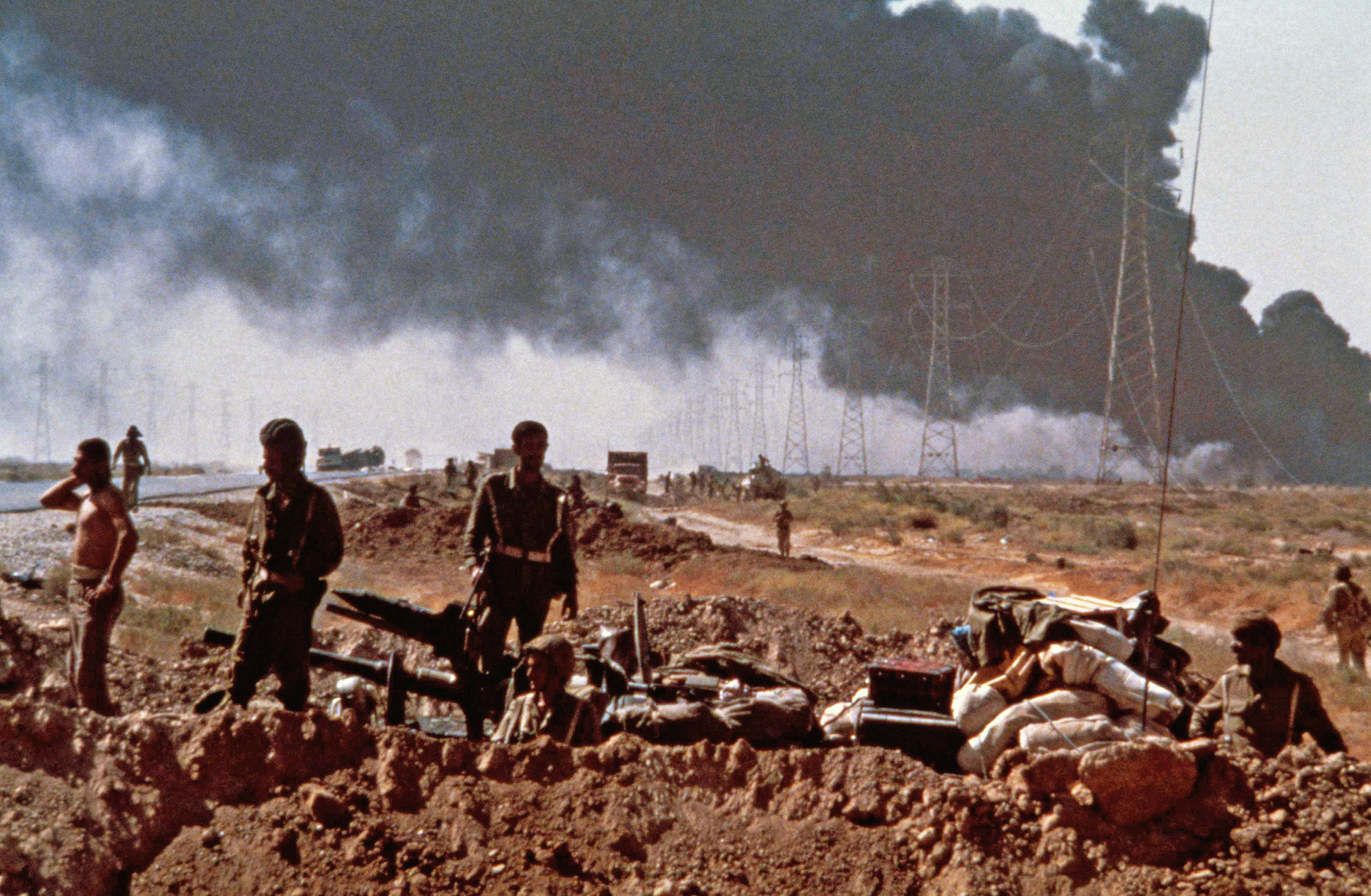 Iraqi soldiers wait by a well-hidden tank in a roadside bunker beside the highway link between Khorramshahr and Abadan on October 17, 1980 in Iran. The background smoke is from the burning pipelines that are used to carry oil from the giant Iranian refinery at Abadan to Ahwas and Teheran. Oil links with major Iranian cities have been a constant target for advancing Iraqi artillery. (AP Photo/Zuhair Saade)