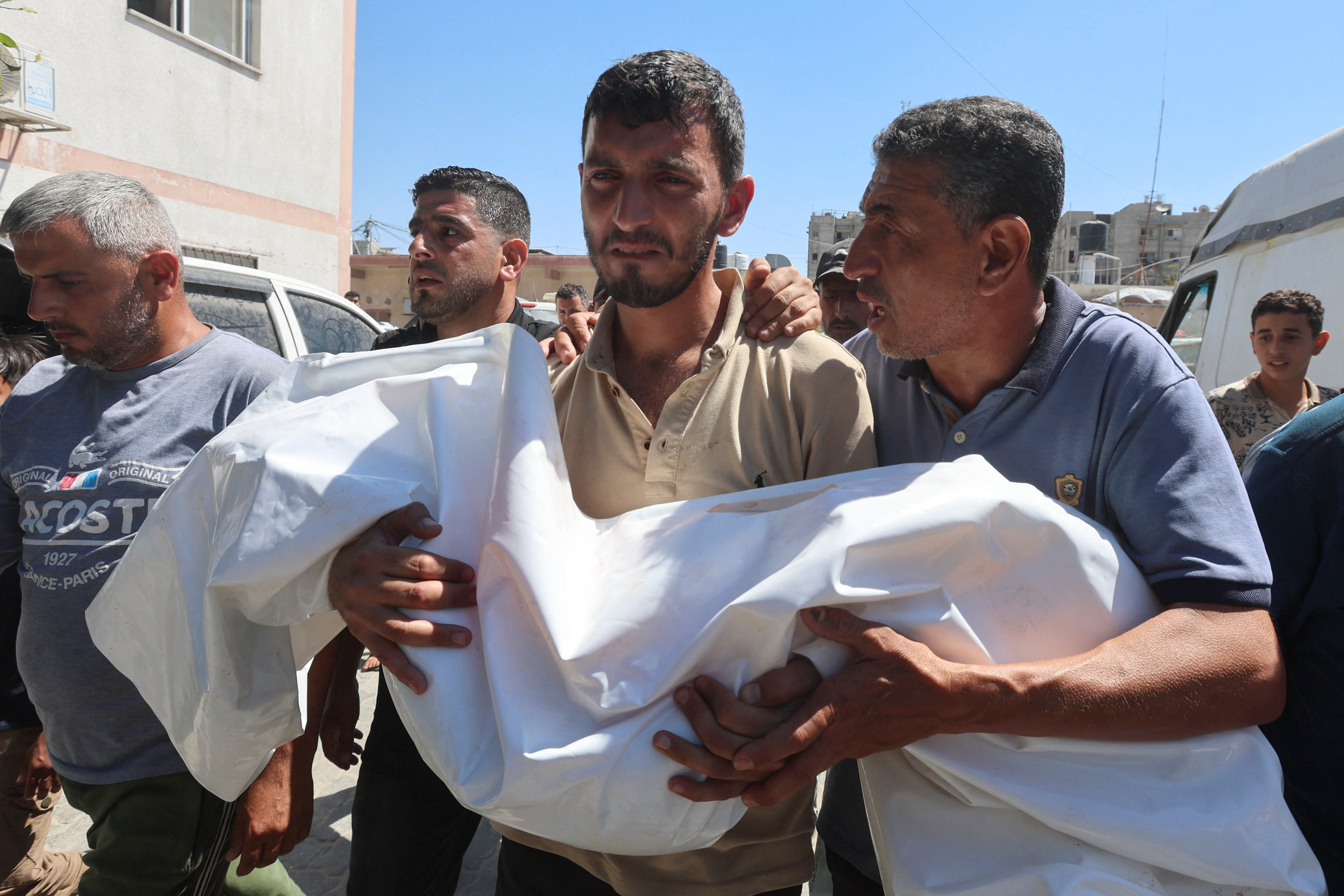 A mourner carries a body.
