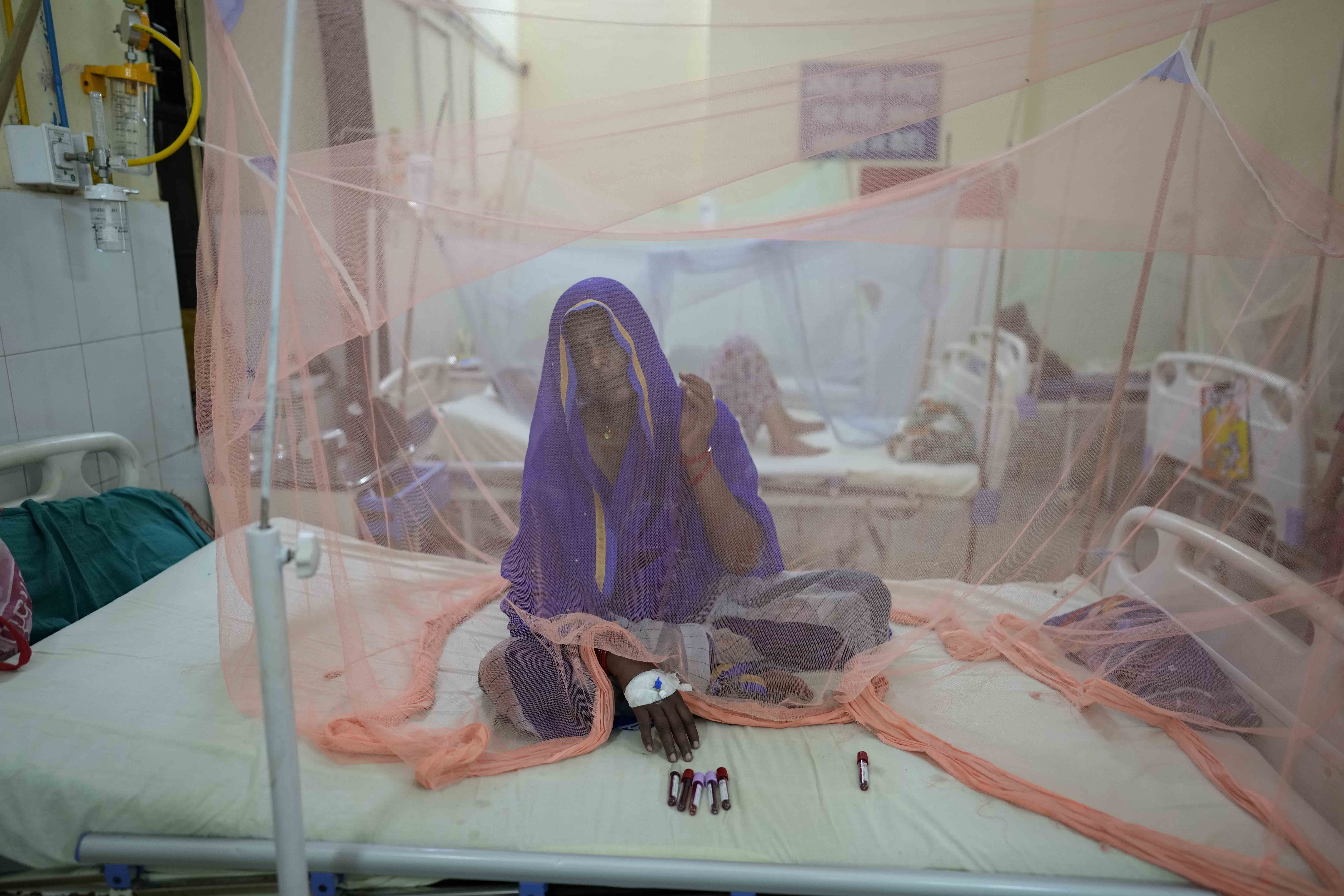 A dengue patient rests under a mosquito net at the dengue ward of the government-run Tej Bahadur Sapru Hospital in Prayagraj, Uttar Pradesh, India, on October 13, 2022