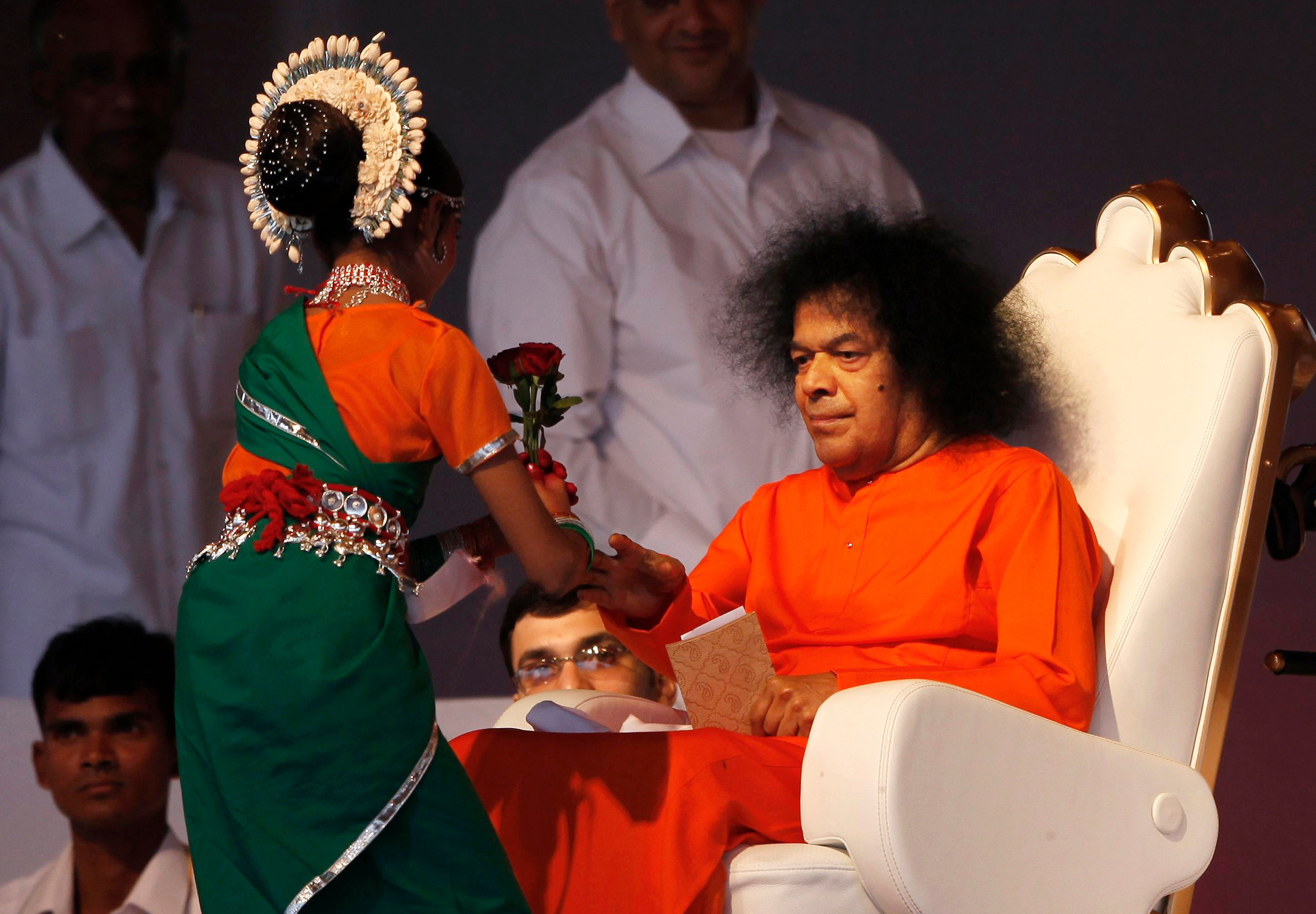 Indian spiritual leader Sathya Sai Baba, right, receives a flower from a girl at a function to meet his devotees in New Delhi on April 10, 2010