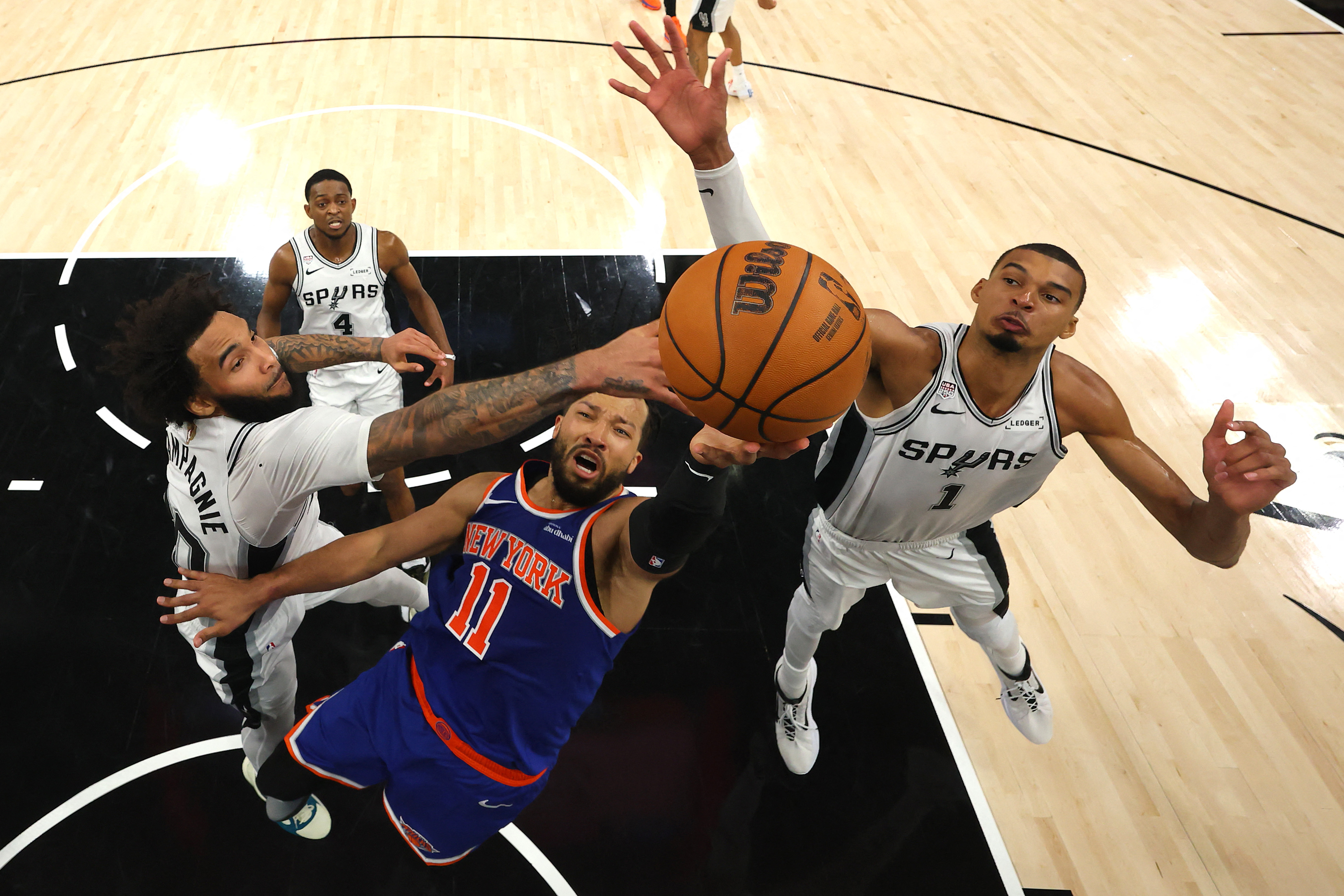 Jalen Brunson #11 of the New York Knicks shoots the ball between Julian Champagnie #30 and Victor Wembanyama #1 of the San Antonio Spurs.