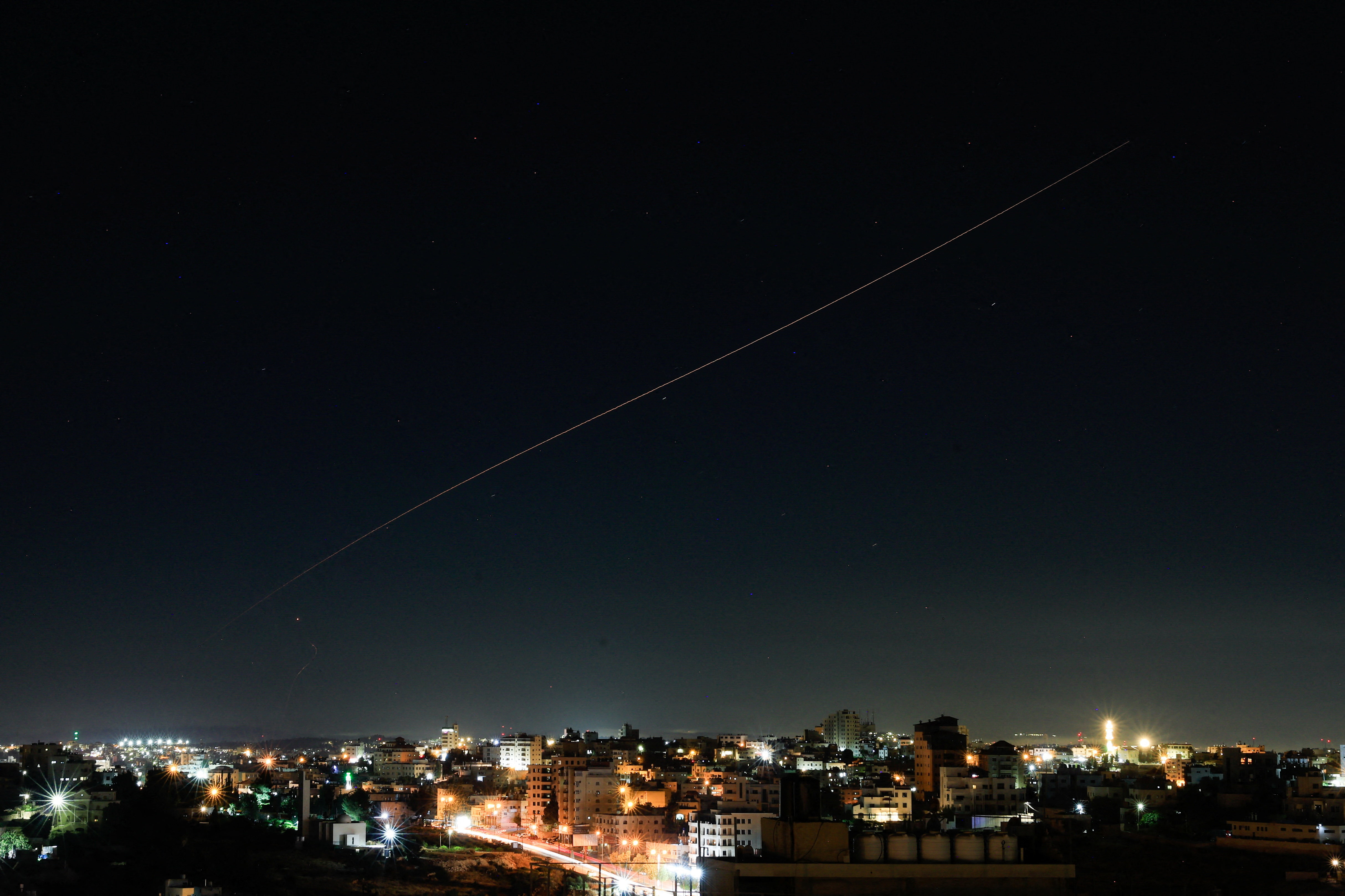 A missile flies in the sky over a city.