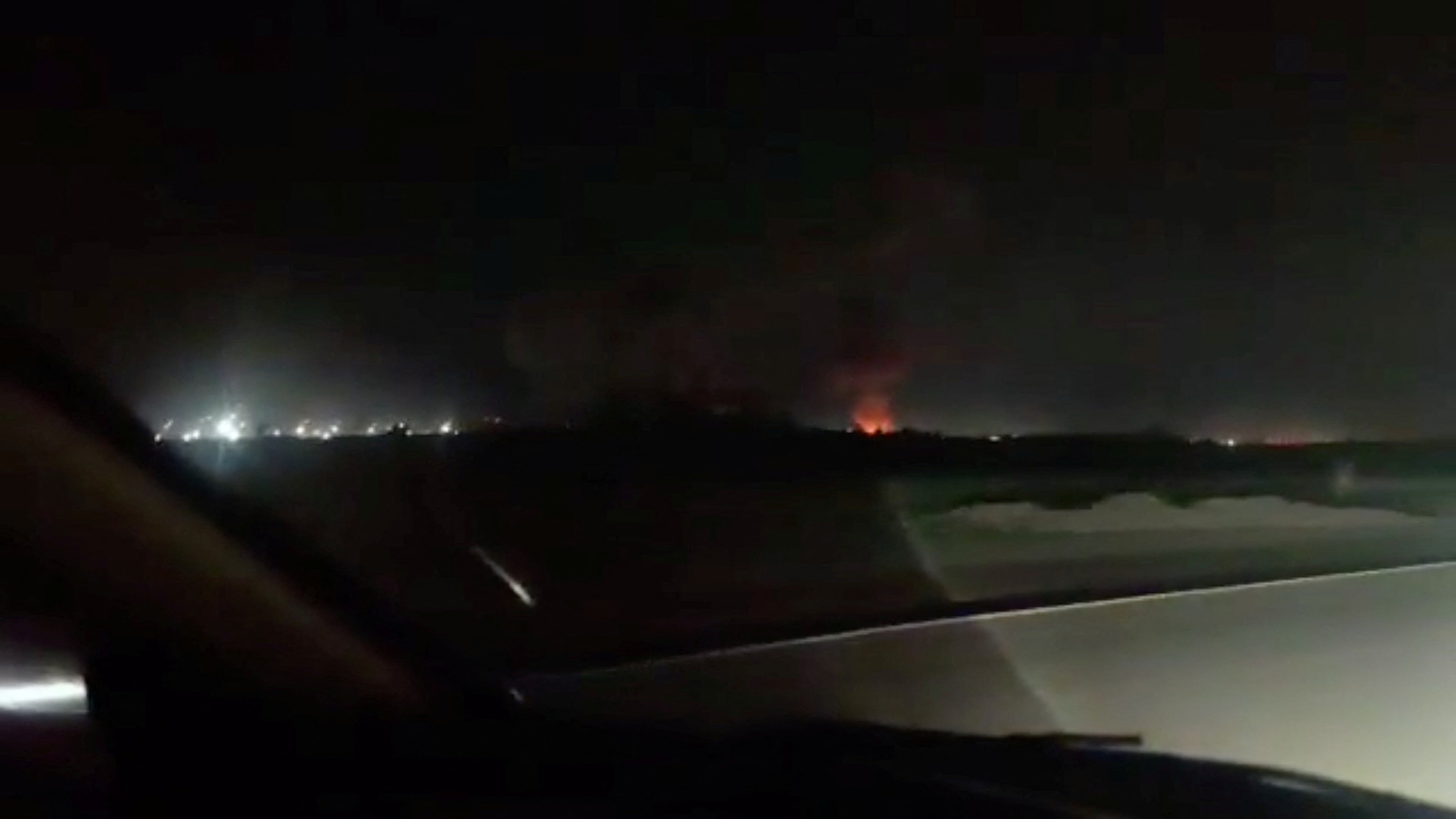 Fire and smoke rise from the direction of Iranshahr airport, as seen from the windscreen of a car, following a strike, near Iranshahr, Iran, in this screengrab from a social media video. Social Media/via REUTERS THIS IMAGE HAS BEEN SUPPLIED BY A THIRD PARTY. NO RESALES. NO ARCHIVES. VERIFICATION: - Road, barriers, drainage ditch and vegetation matched satellite imagery - Coordinates: 27.238113888619836, 60.70817332026714 - Date not verified - However, Iran’s semi-official Mehr News Agency reported attack on the city's airport facilities, citing local official - No older version of the footage was found posted online before July 9
