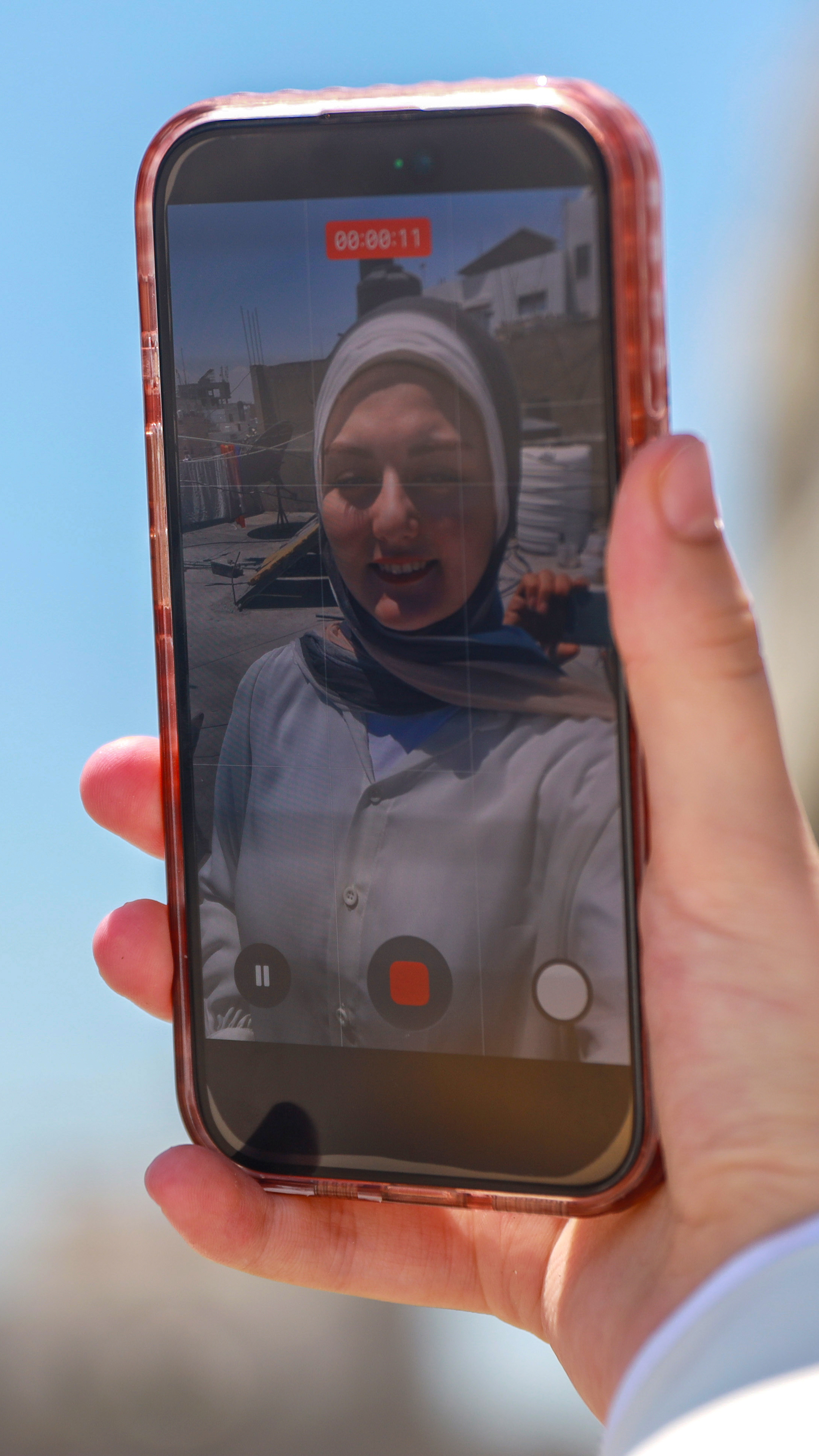 Eman Lulu records a video in Gaza City, where her phone has become both a lifeline and a tool for documenting daily life during Israel's genocide in Gaza