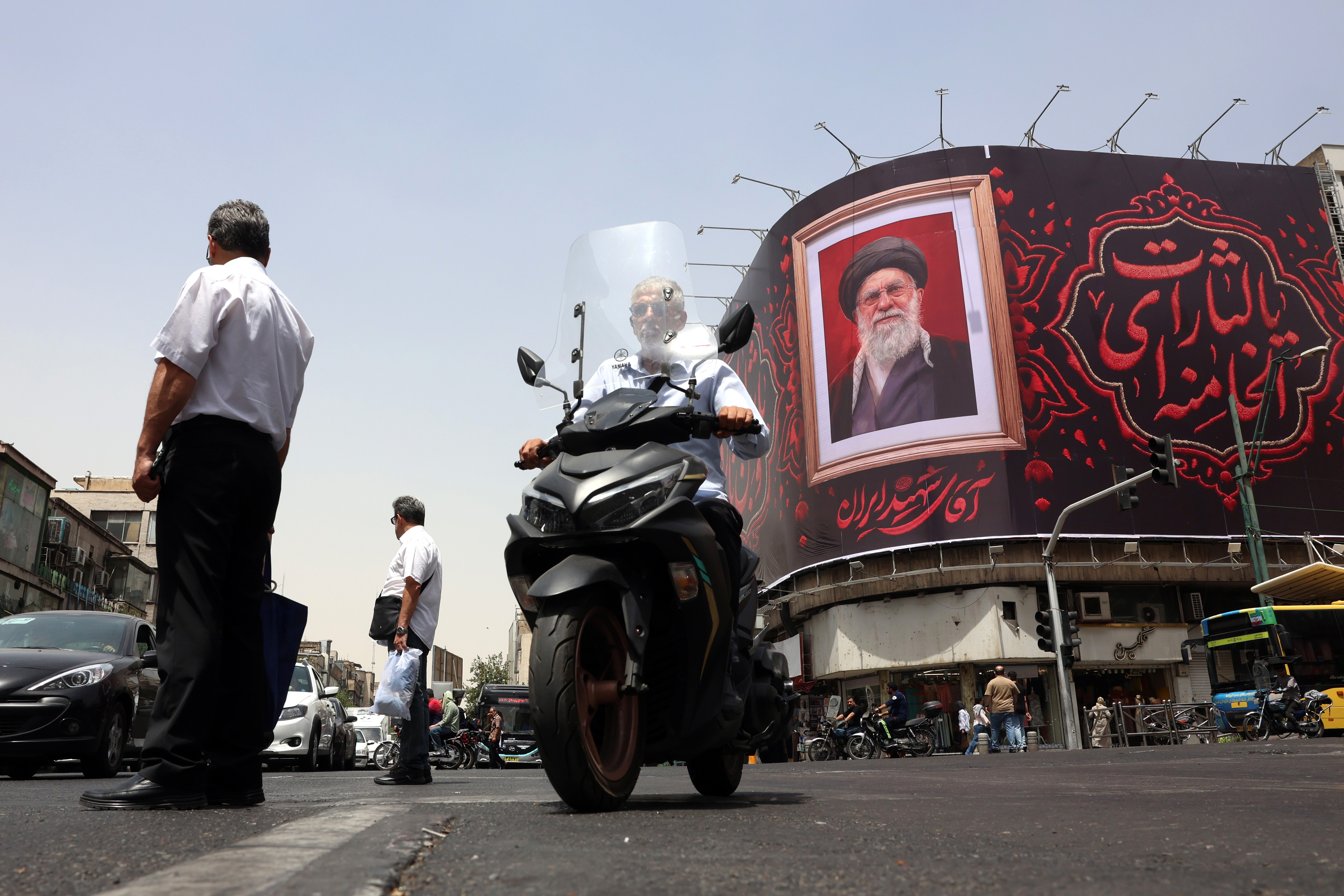 epa13079707 Iranian people pass a large-scale banner of late Iranian Supreme Leader Ayatollah Ali Khamenei, ahead of his funeral in Tehran, Iran, 02 July 2026. Iran is set to hold a multi-day state funeral from 04 to 09 July 2026 for the Iranian supreme leader assassinated on 28 February. EPA/ABEDIN TAHERKENAREH RESTRICTIONS: NO Access Israel Media/Persian Language TV Stations Outside Iran/Strictly No Access BBC Persian/VOA Persian/Manoto TV/Iran International TV. (As mandated by Iran's Directorate General for Foreign Media) --