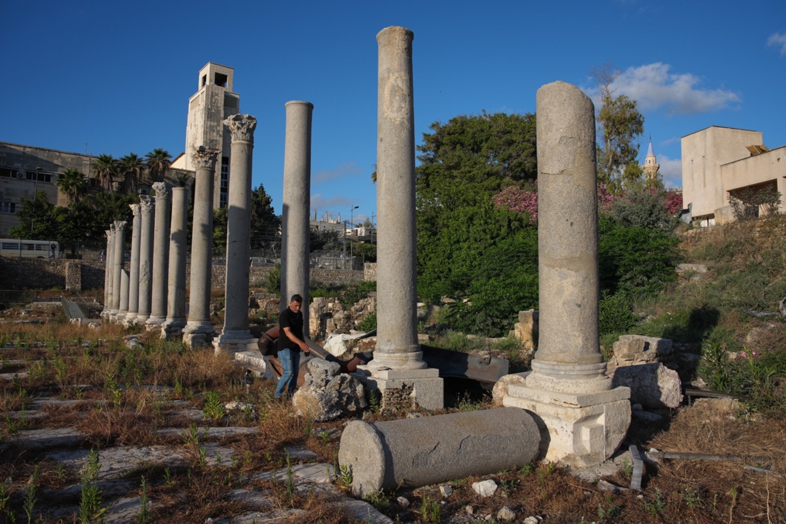 Adnan Istanbuli, an employee at the Directorate General of Antiquities, inspects a Roman-era column after part of its capital was knocked off and fell to the ground at an archaeological site lightly damaged in an Israeli strike nearby last week, in the southern port city of Tyre, Lebanon, Thursday, June 18, 2026. [AP Photo/Hassan Ammar]