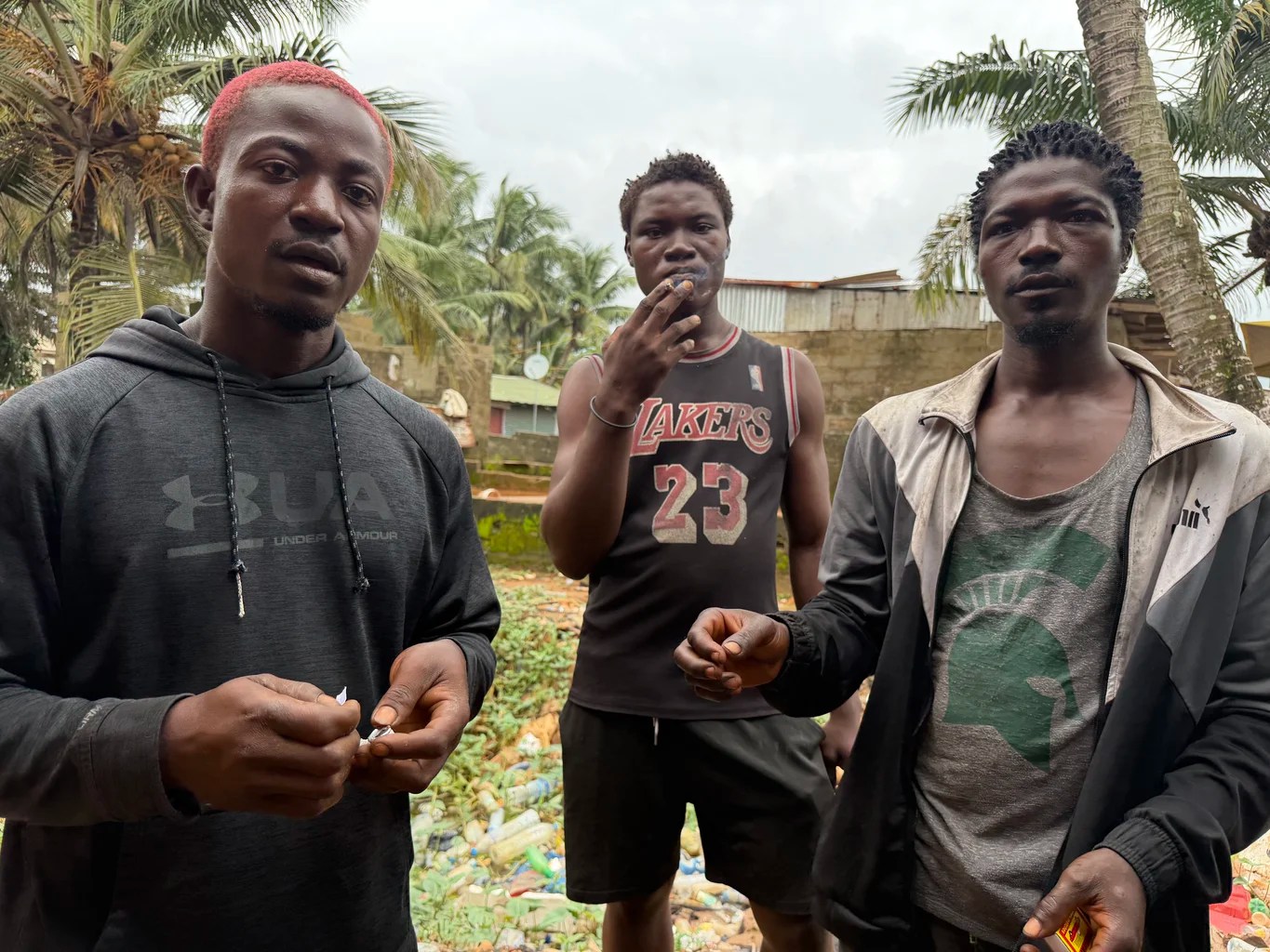 Abraham Jackson, 26, far right, sits with other kush users at a drug den in Monrovia. Users are known locally as zogos. [Lennart Dodoo/Al Jazeera]
