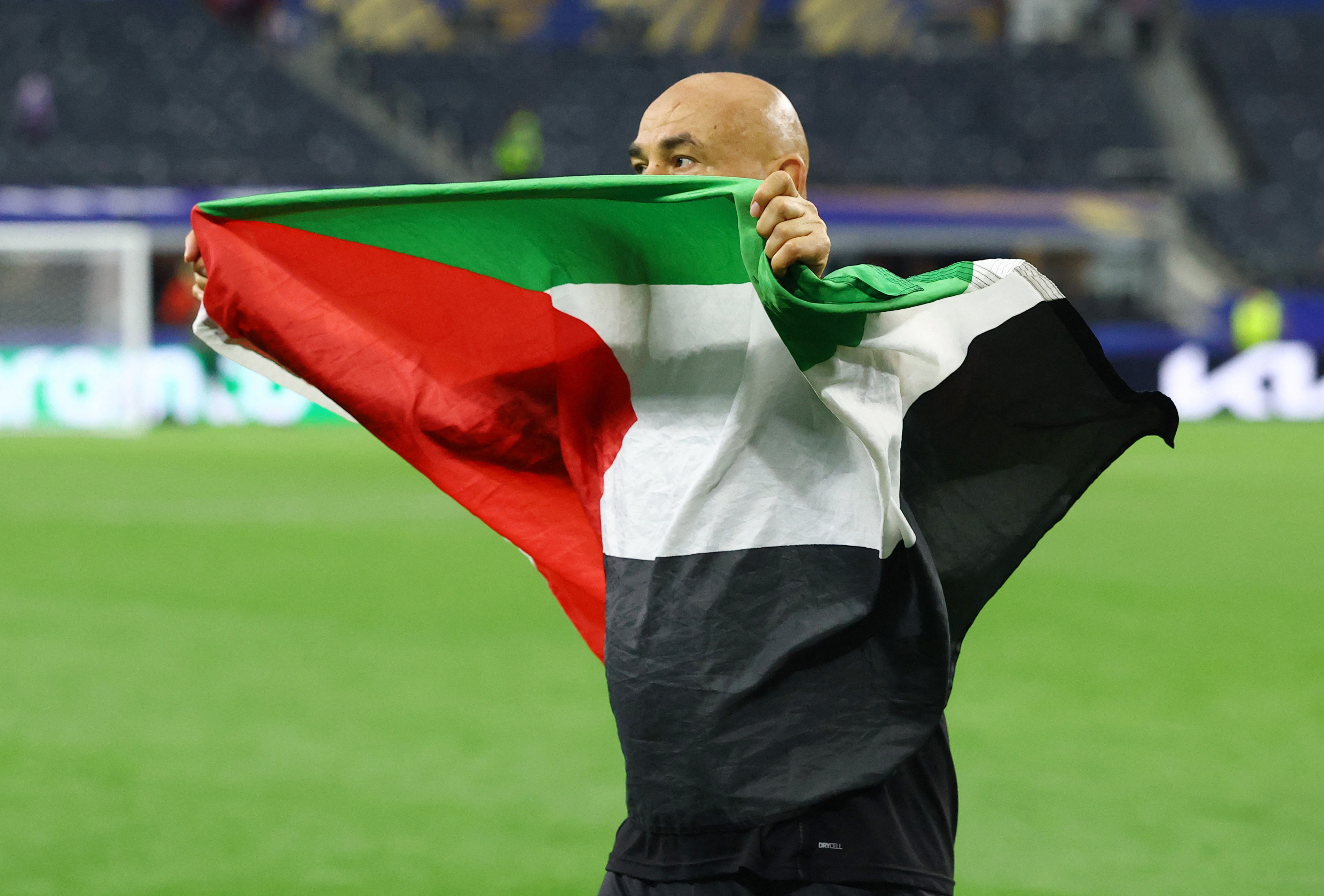 Soccer Football - FIFA World Cup 2026 - Round of 32 - Australia v Egypt - Dallas Stadium, Arlington, Texas, U.S. - July 3, 2026 Egypt coach Hossam Hassan celebrates with a Palestine flag after the match as Egypt qualify for the Round of 16 stage of the World Cup REUTERS/Hannah Mckay
