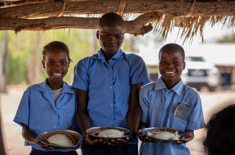Schoolchildren pose with nutrition meals provided by the United Nations World Food Programme as communities recover from flooding in Mozambique. [WFP Mozambique]