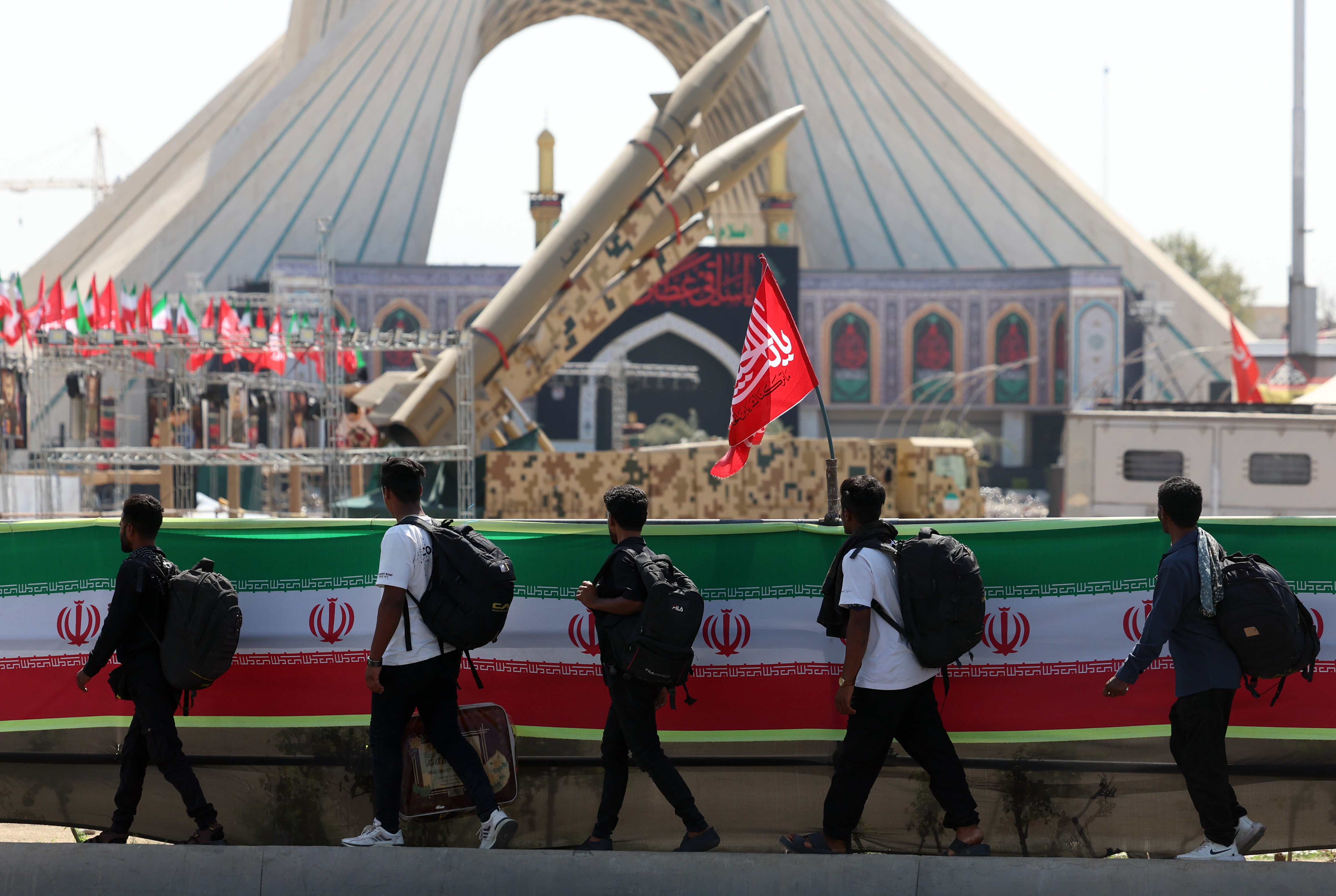 People walk past Iranian missiles