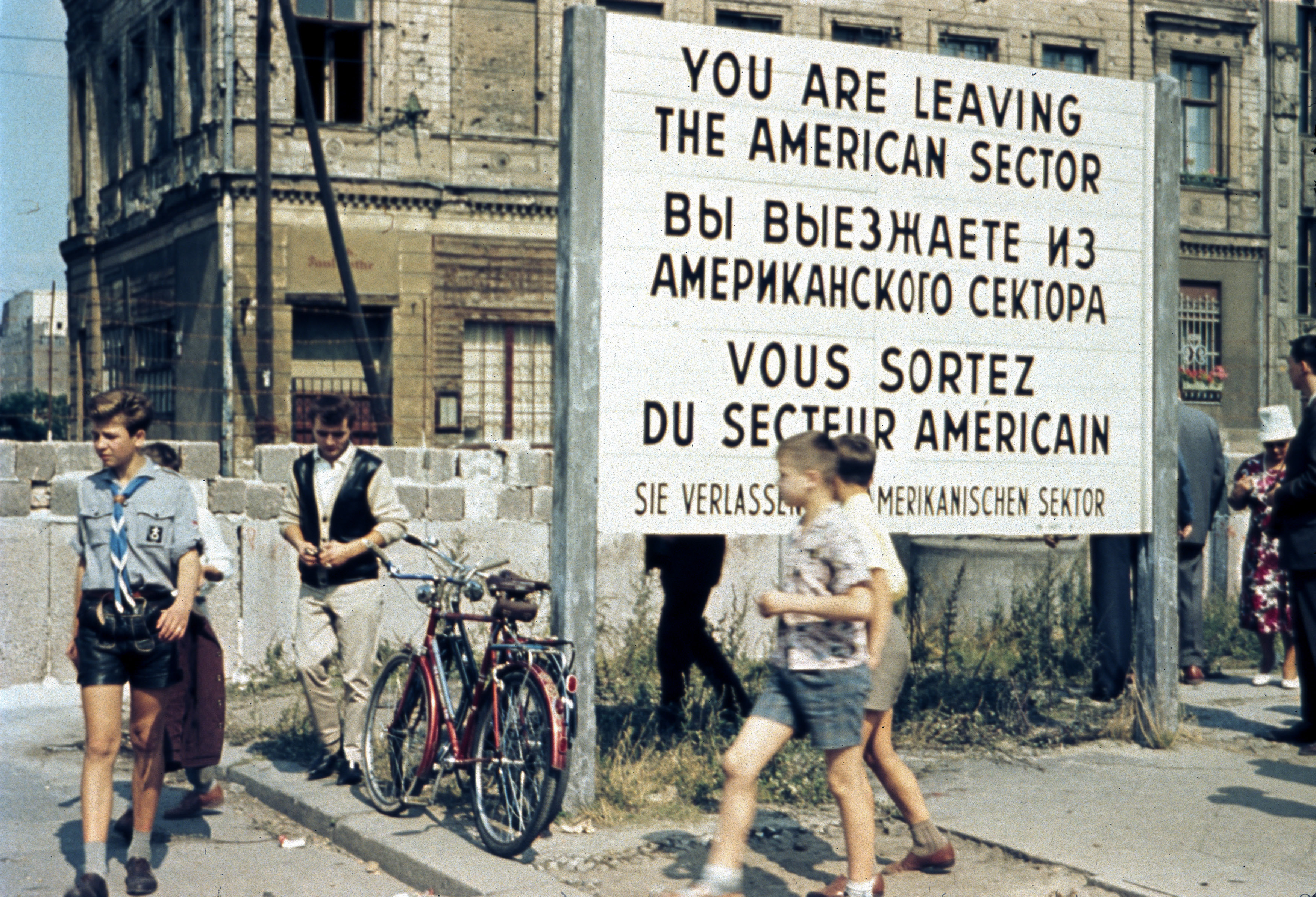 West Berliners walk in front of the Berlin Wall at the Allied checkpoint Charlie in Berlin in July 1963 [Norbert Bensch/ REUTERS]