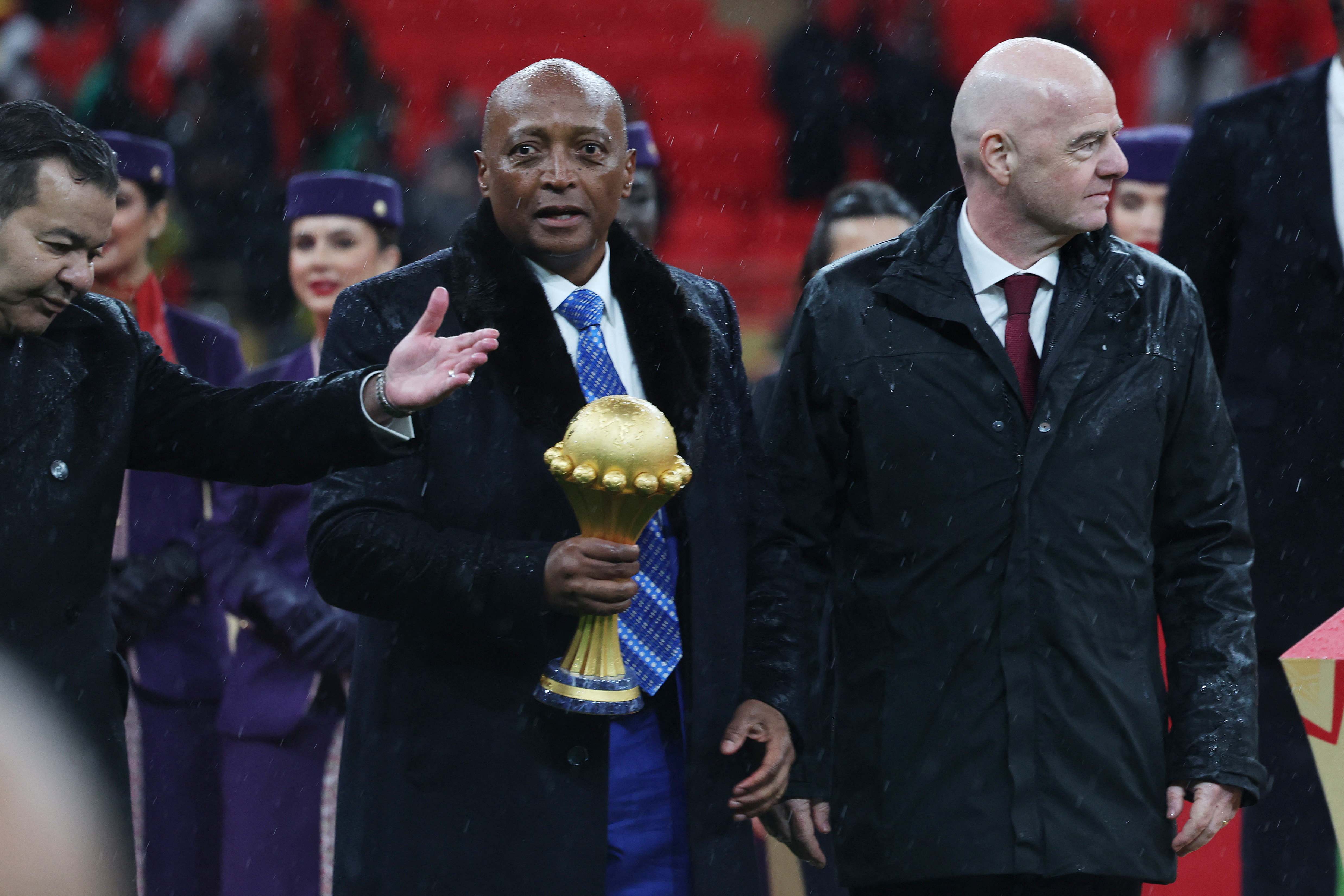CAF president Patrice Motsepe holds the Africa Cup of Nations trophy as he walks alongside FIFA president Gianni Infantino during the presentation after January’s final