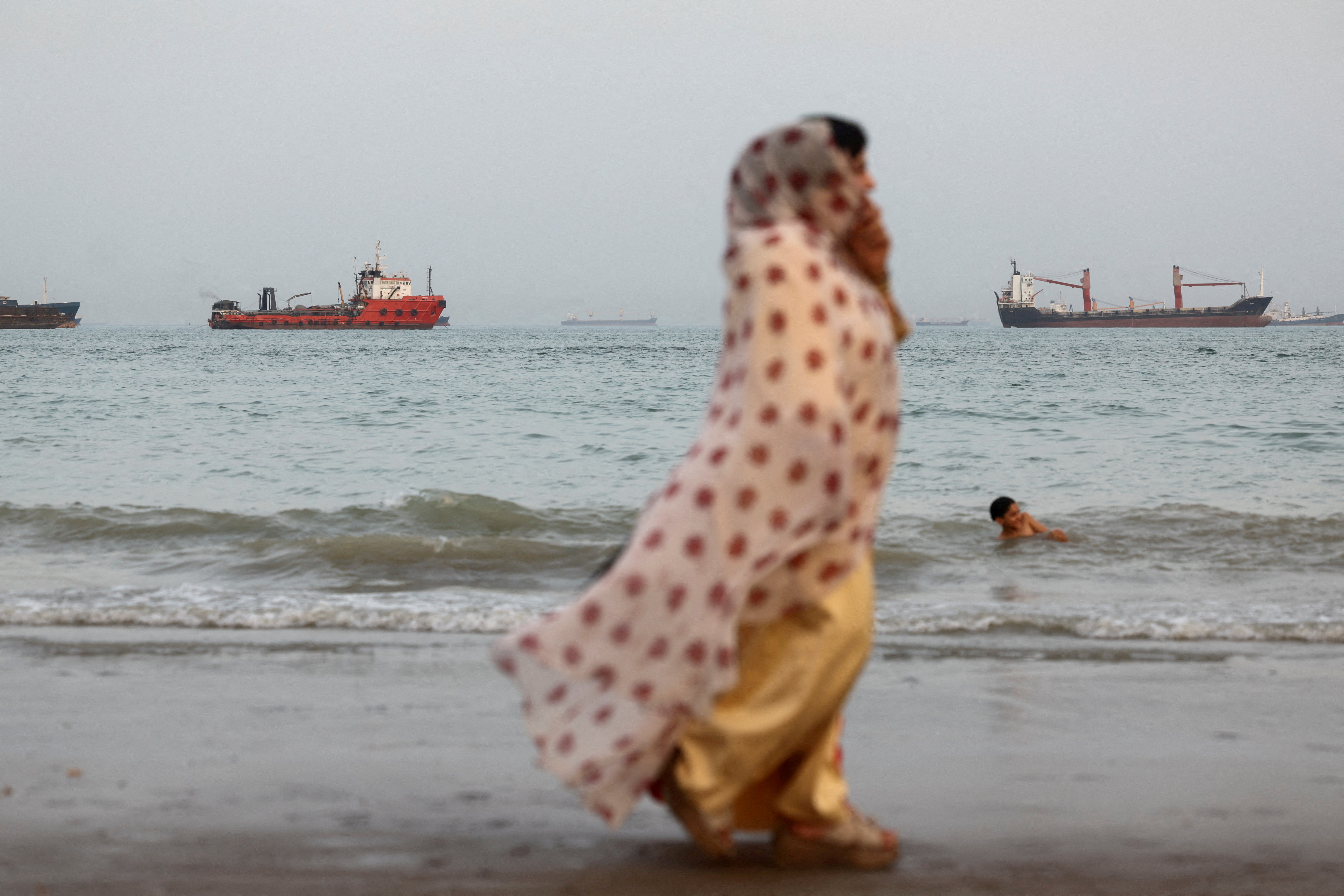 FILE PHOTO: People walk on the beach, with vessels in the Strait of Hormuz visible near the beach of Bandar Abbas, Iran, May 22, 2026. Majid Asgaripour/WANA (West Asia News Agency) via REUTERS ATTENTION EDITORS - THIS PICTURE WAS PROVIDED BY A THIRD PARTY/File Photo