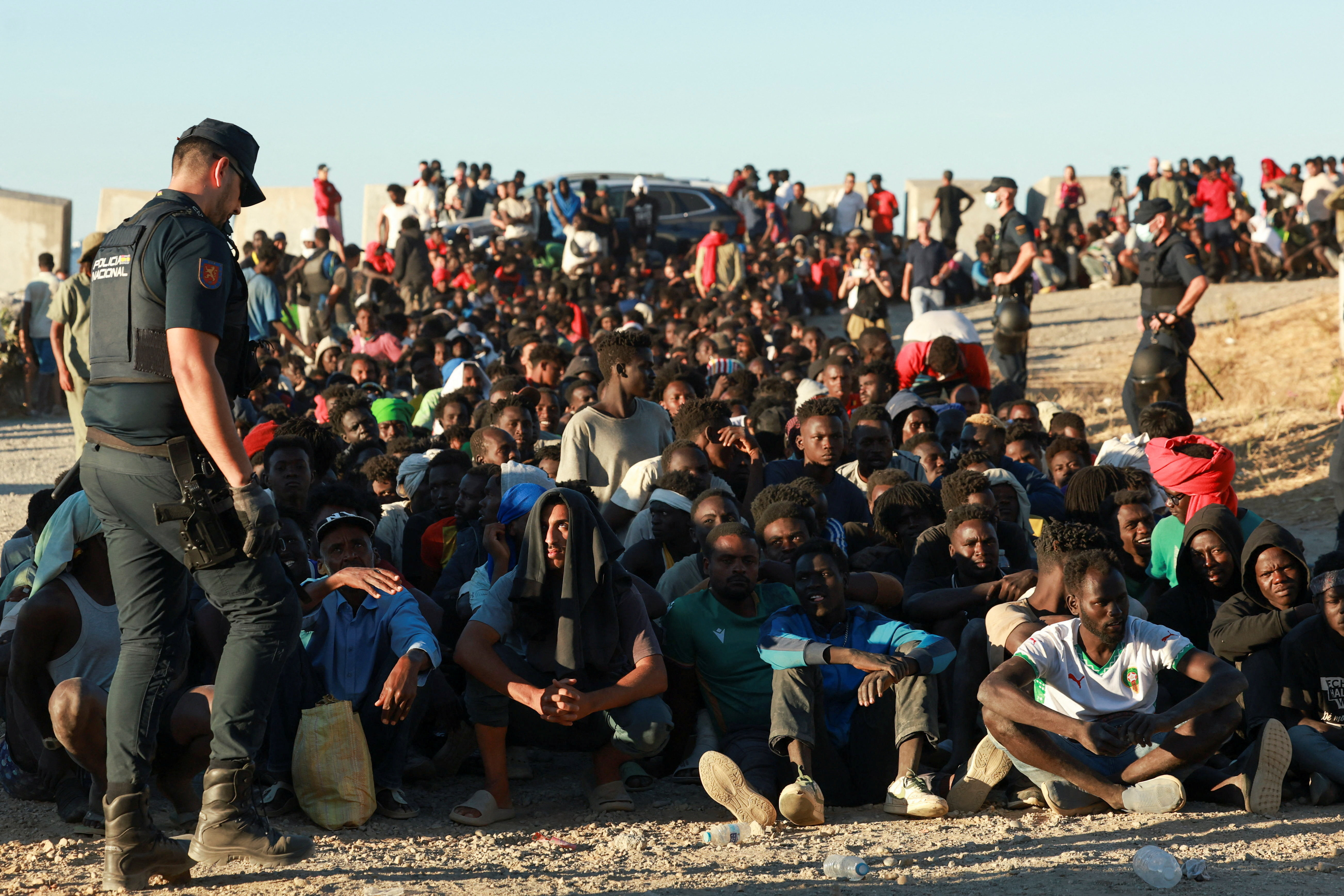 Migrants wait in line to receive food and beverage from the Red Cross, following mass crossings of migrants on foot and by sea from Morocco into Spanish territory, in Ceuta, Spain, August 3, 2026. REUTERS/Violeta Santos Moura