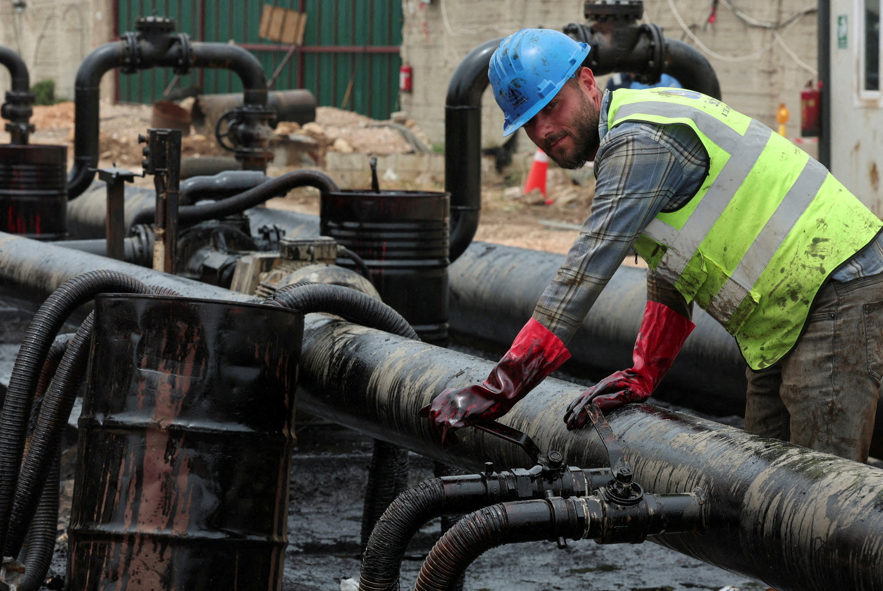 A man works during the unloading of oil from trucks arriving from Iraq at the Baniyas oil terminal, in Baniyas, Syria, May 14, 2026
