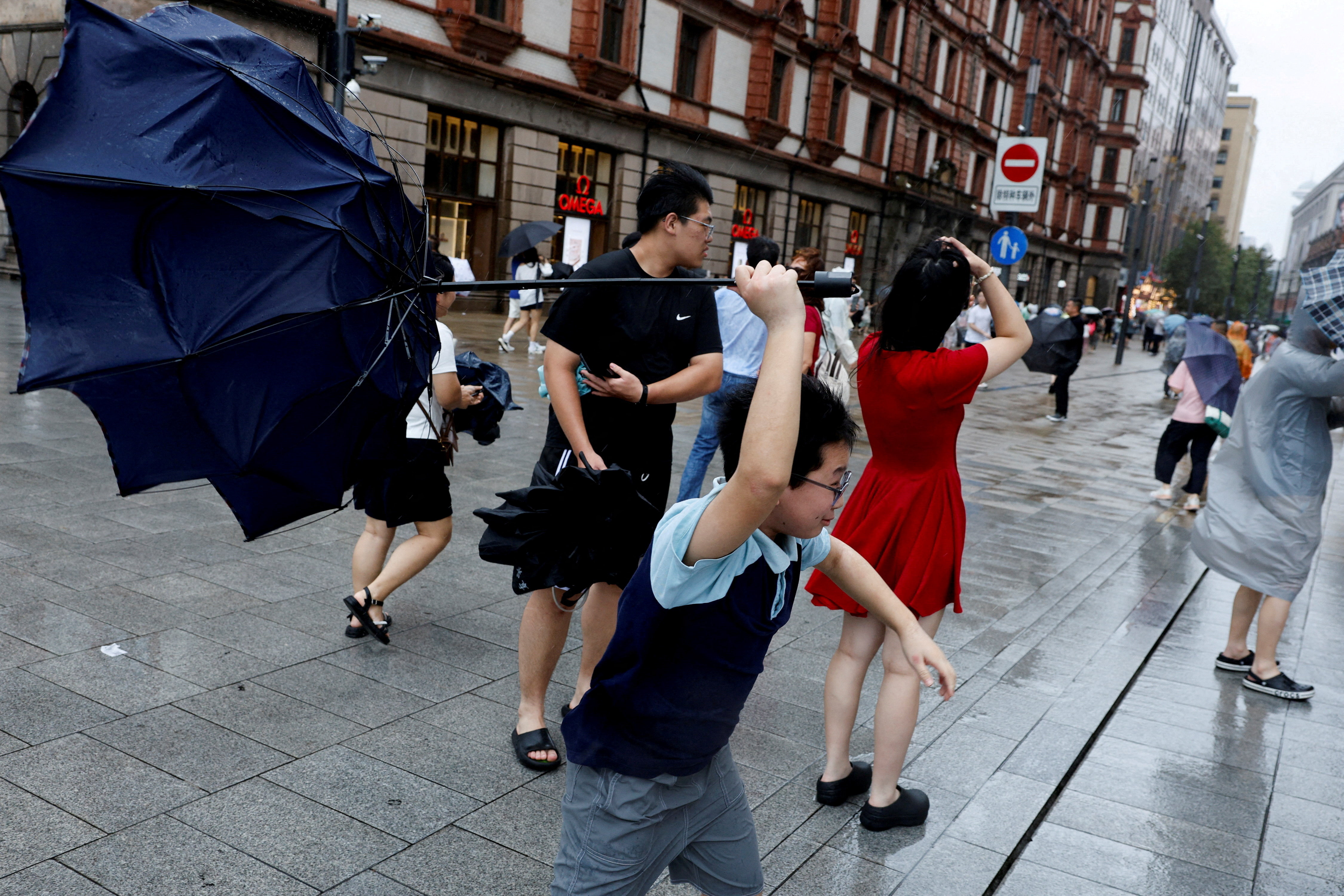 A person holds an inverted umbrella as winds intensify ahead of the arrival of Typhoon Dolphin in Shanghai, China