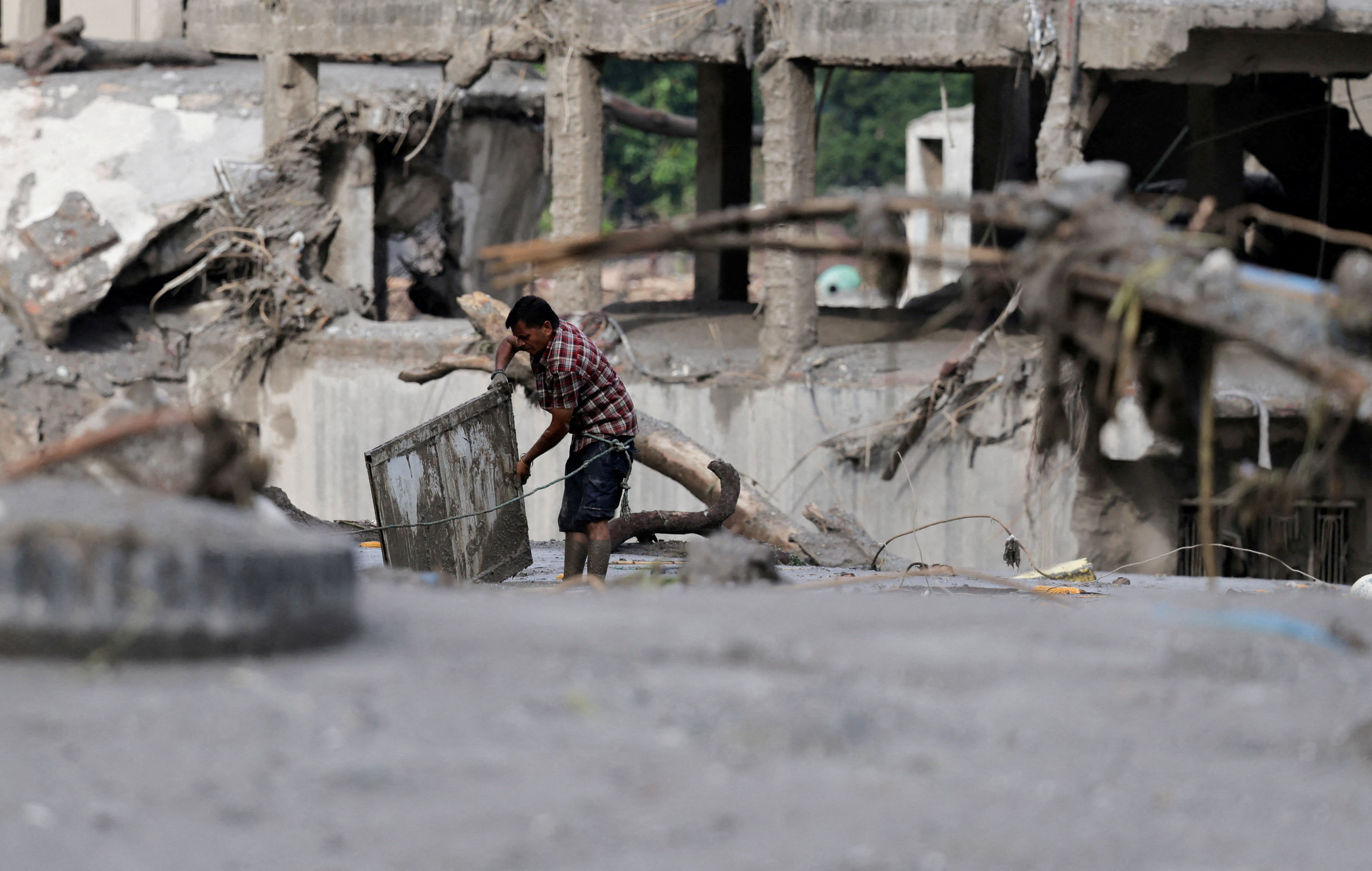 A man salvages his belongings from mud following devastating floods.