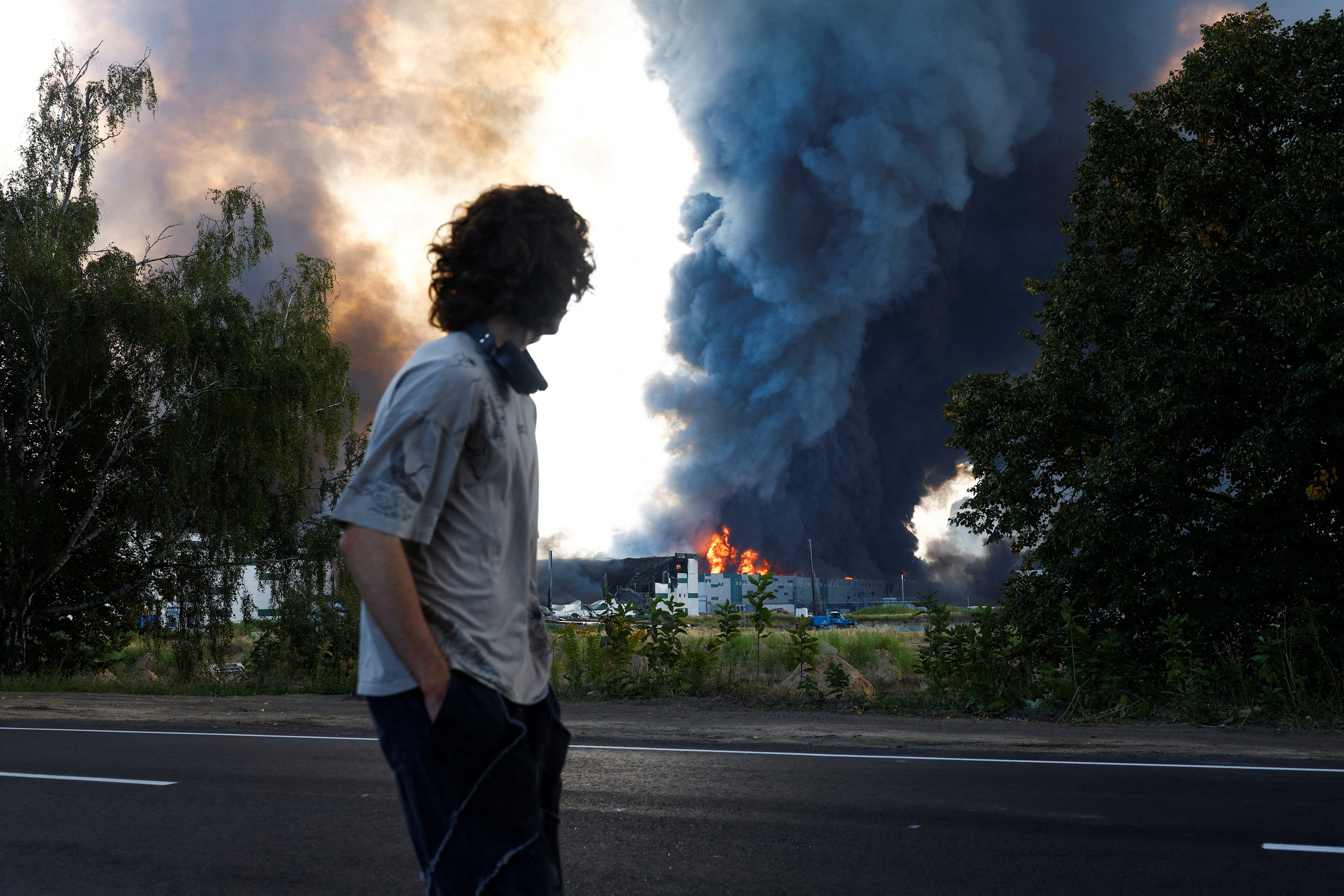 A man looks on as smoke rises over a warehouse, which was hit by a Russian drone strike, amid Russia's attack on Ukraine, in Kyiv region, Ukraine, August 27, 2026. REUTERS/Valentyn Ogirenko TPX IMAGES OF THE DAY