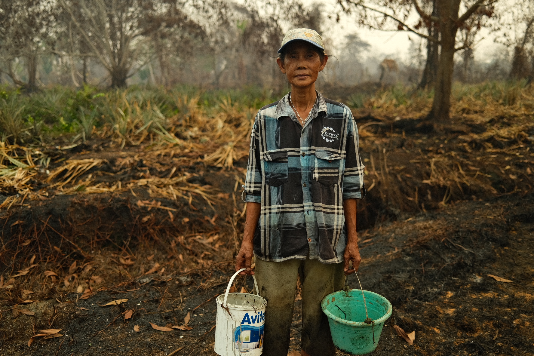 Salma carries buckets of water near farmland as wildfires affect West Kalimantan