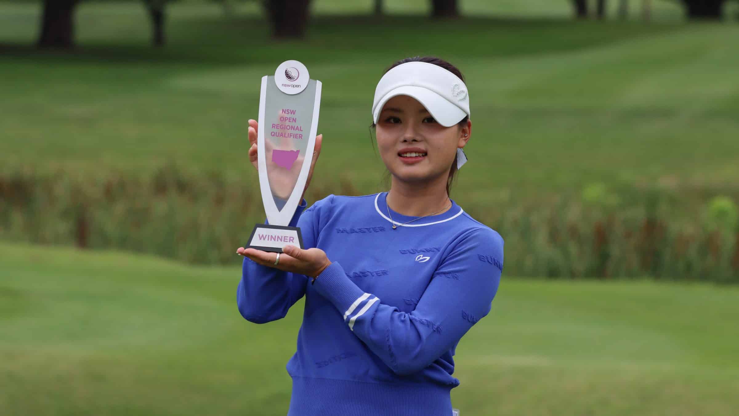 Jessica Bang poses with a trophy on a golf course.