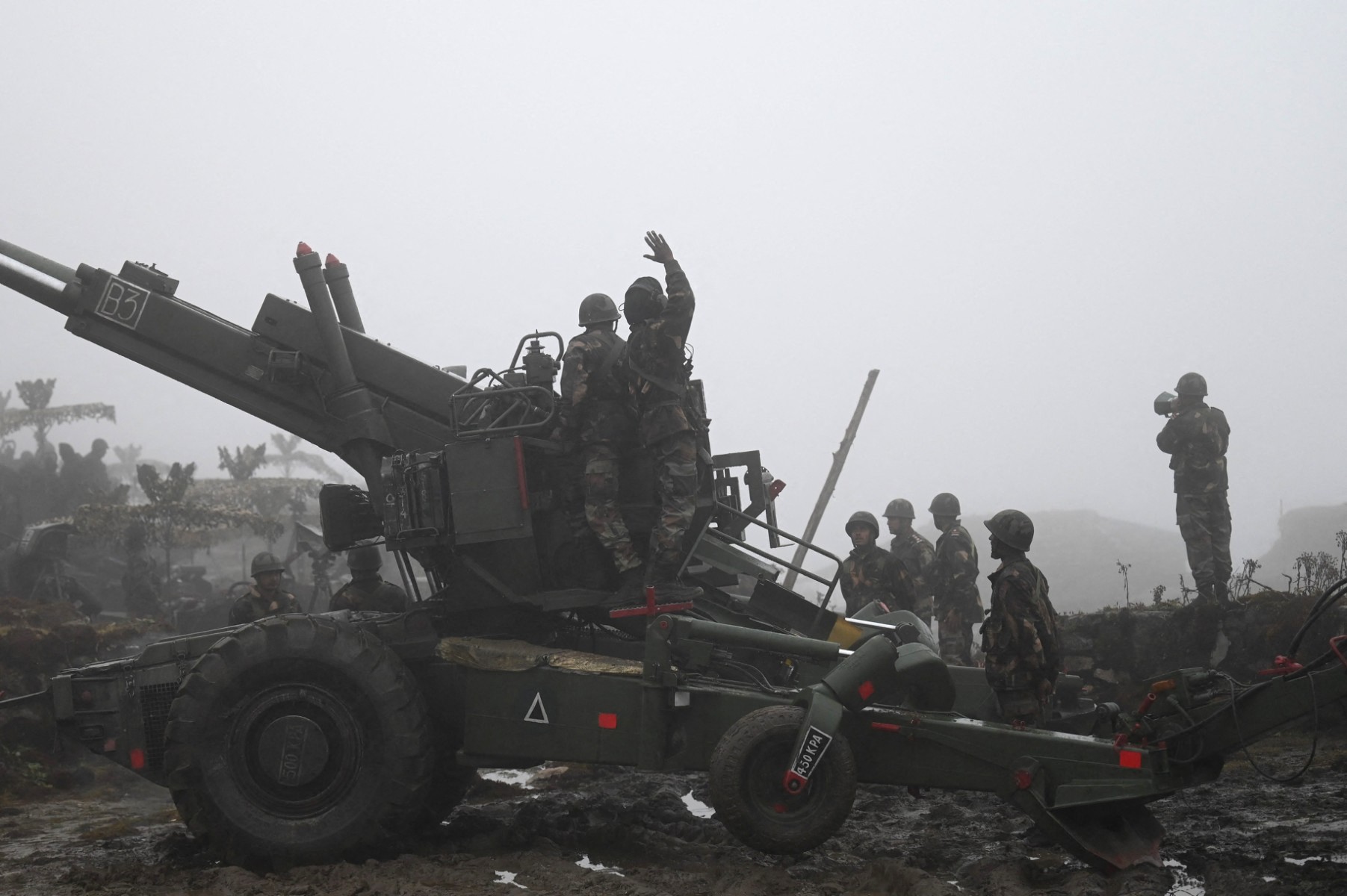 Soldiers stand with military equipment