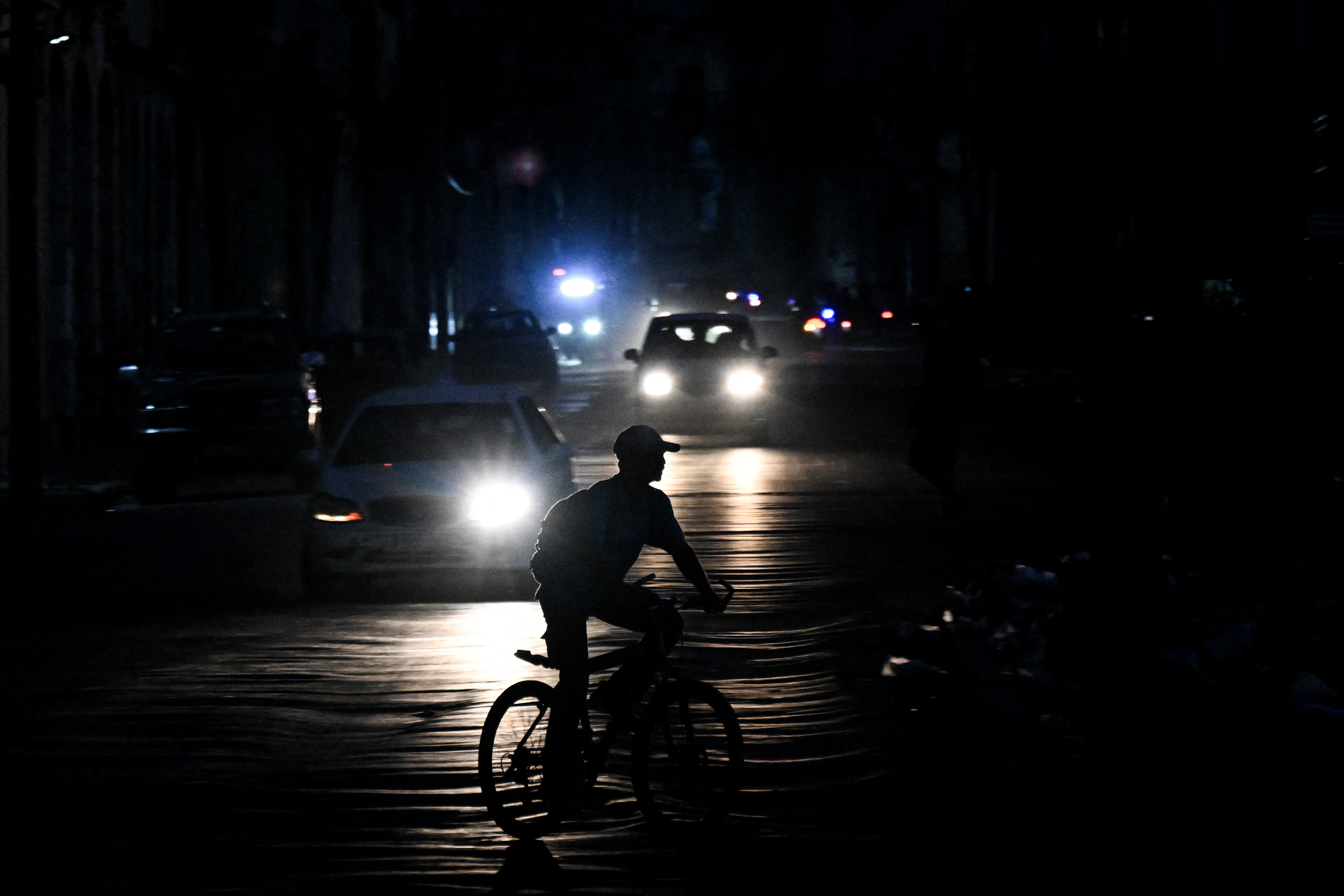 A man rides his bicycle down a street during a blackout in Havana on August 1, 2026. [YAMIL LAGE / AFP]