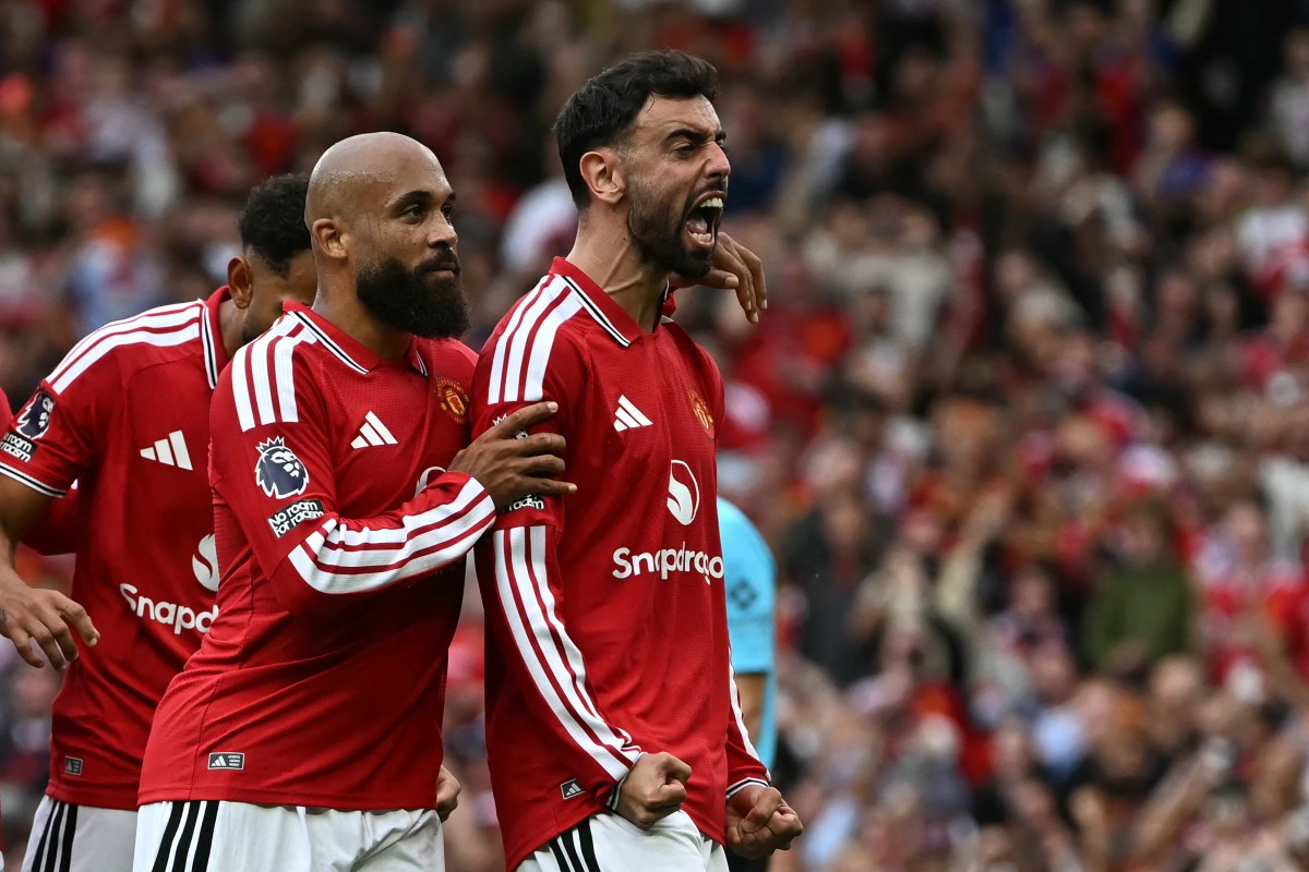Manchester United's Portuguese midfielder #08 Bruno Fernandes (R) celebrates after scoring the team's third goal on a penalty shot during the English Premier League football match