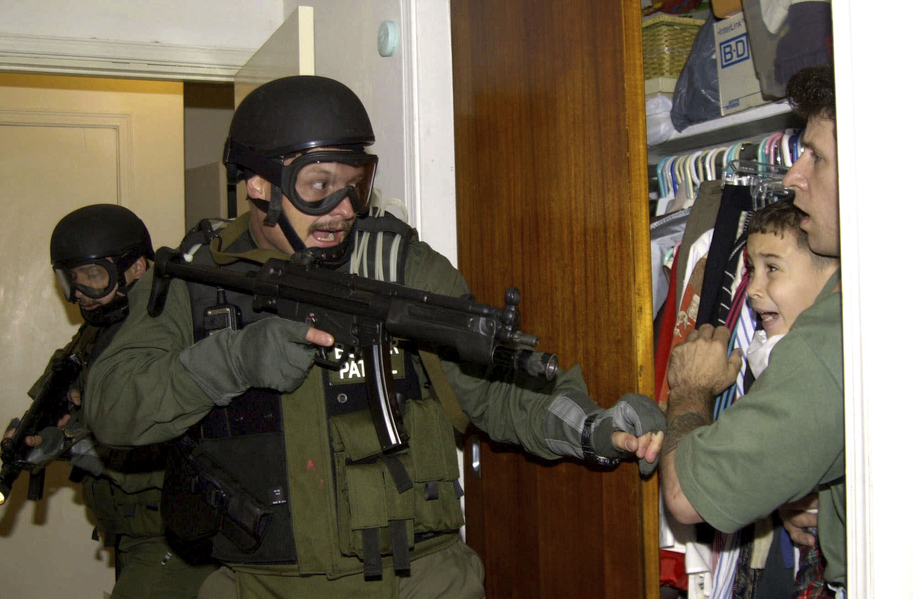 FILE - Elian Gonzalez is held in a closet by Donato Dalrymple, one of the two men who rescued the boy from the ocean, right, as government officials search the home of Lazaro Gonzalez for the young boy, in Miami, Florida, April 22, 2000. Twenty three years after González became the center of a dramatic diplomatic custody battle between Cuba and the United States, the young Cuban is now headed to his country’s congress with hopes of representing his people at a time of record migration and heightened tension between the two seaside neighbors. (AP Photo/Alan Diaz, File)